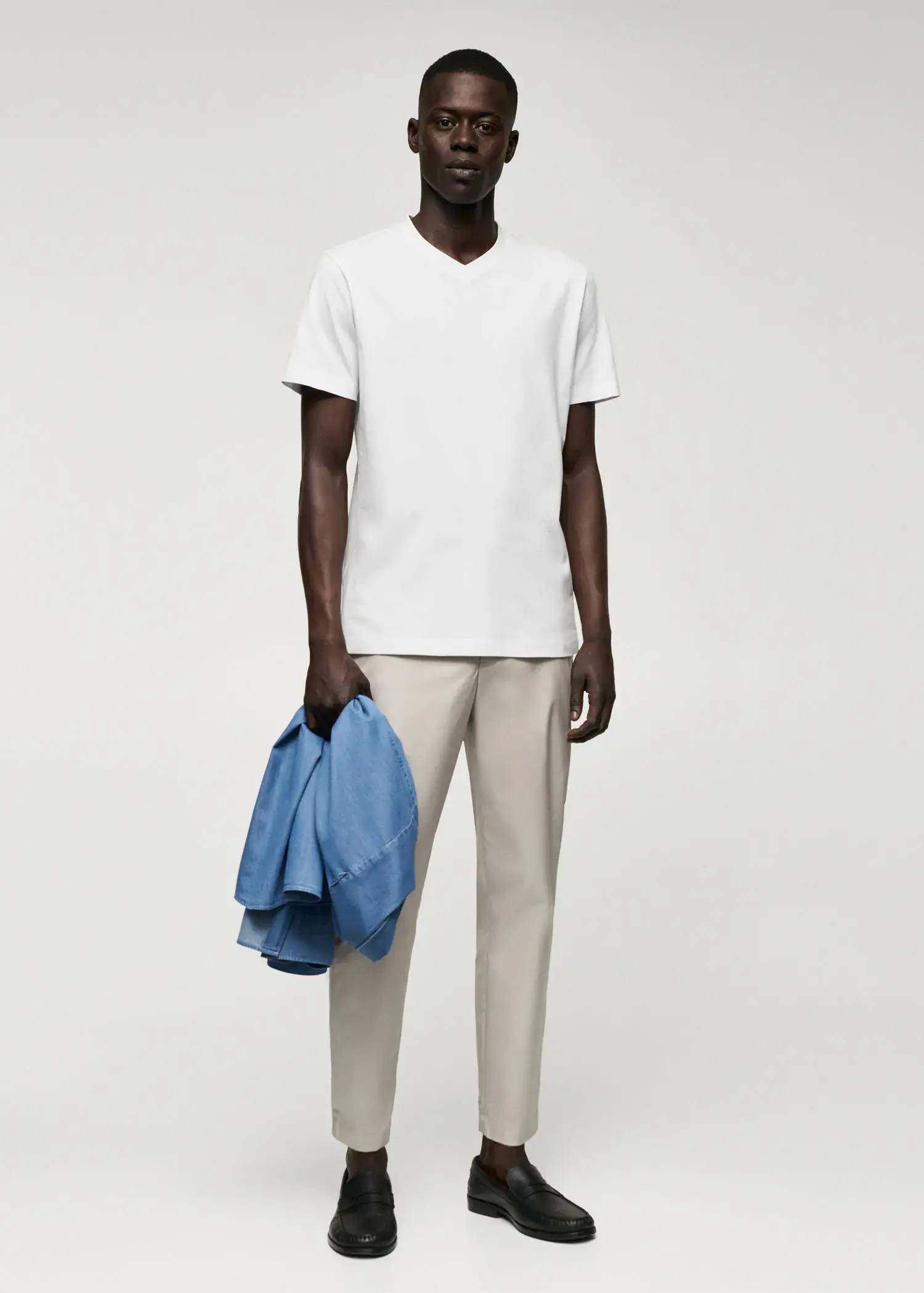 Mango Basic cotton V-neck T-shirt. a man in a white t-shirt holding a blue jacket. 