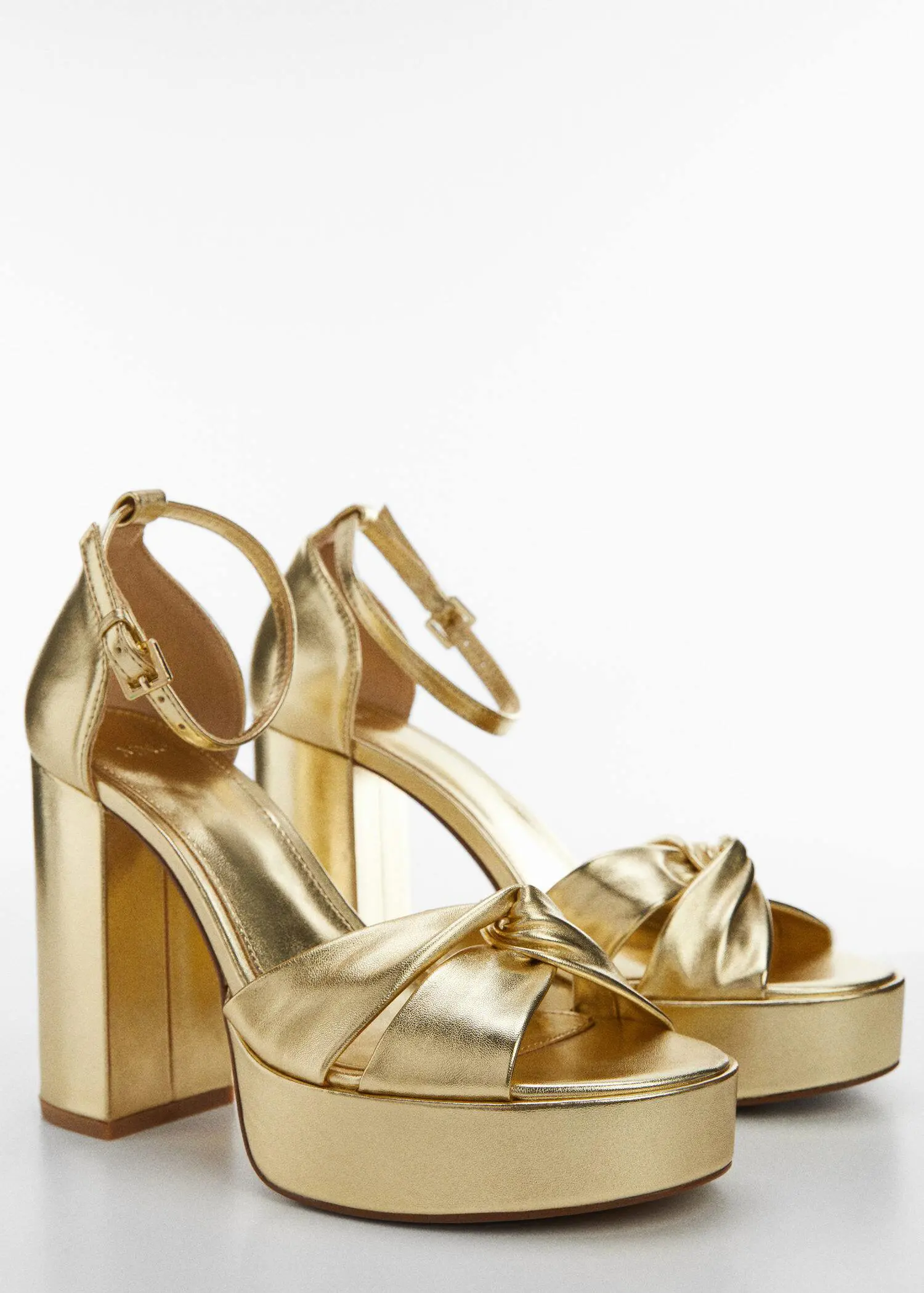 Mango Metallic heel sandals. a pair of gold shoes on a white background 