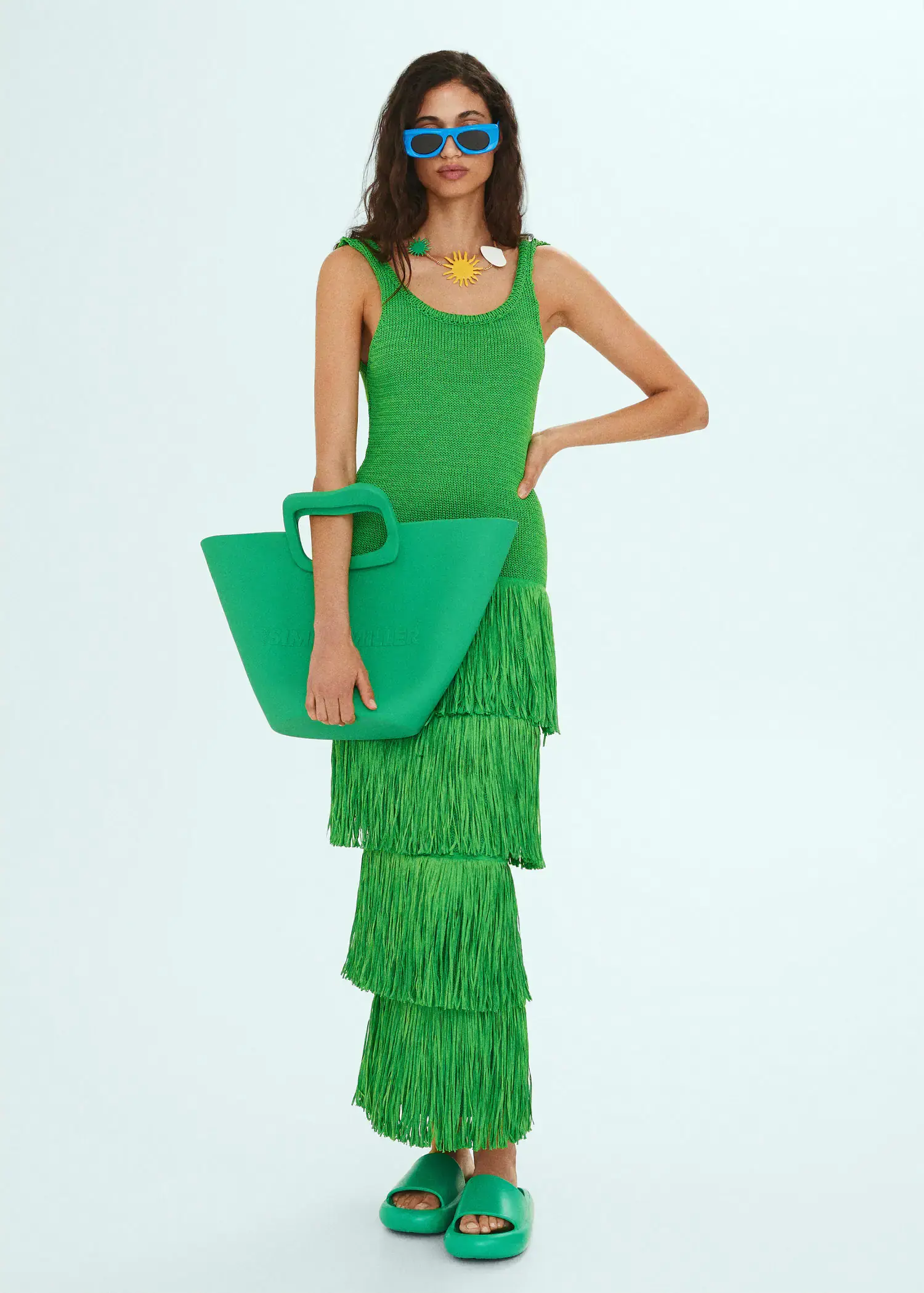 Mango Knitted dress with fringe design. a woman in a green dress holding a green bag. 