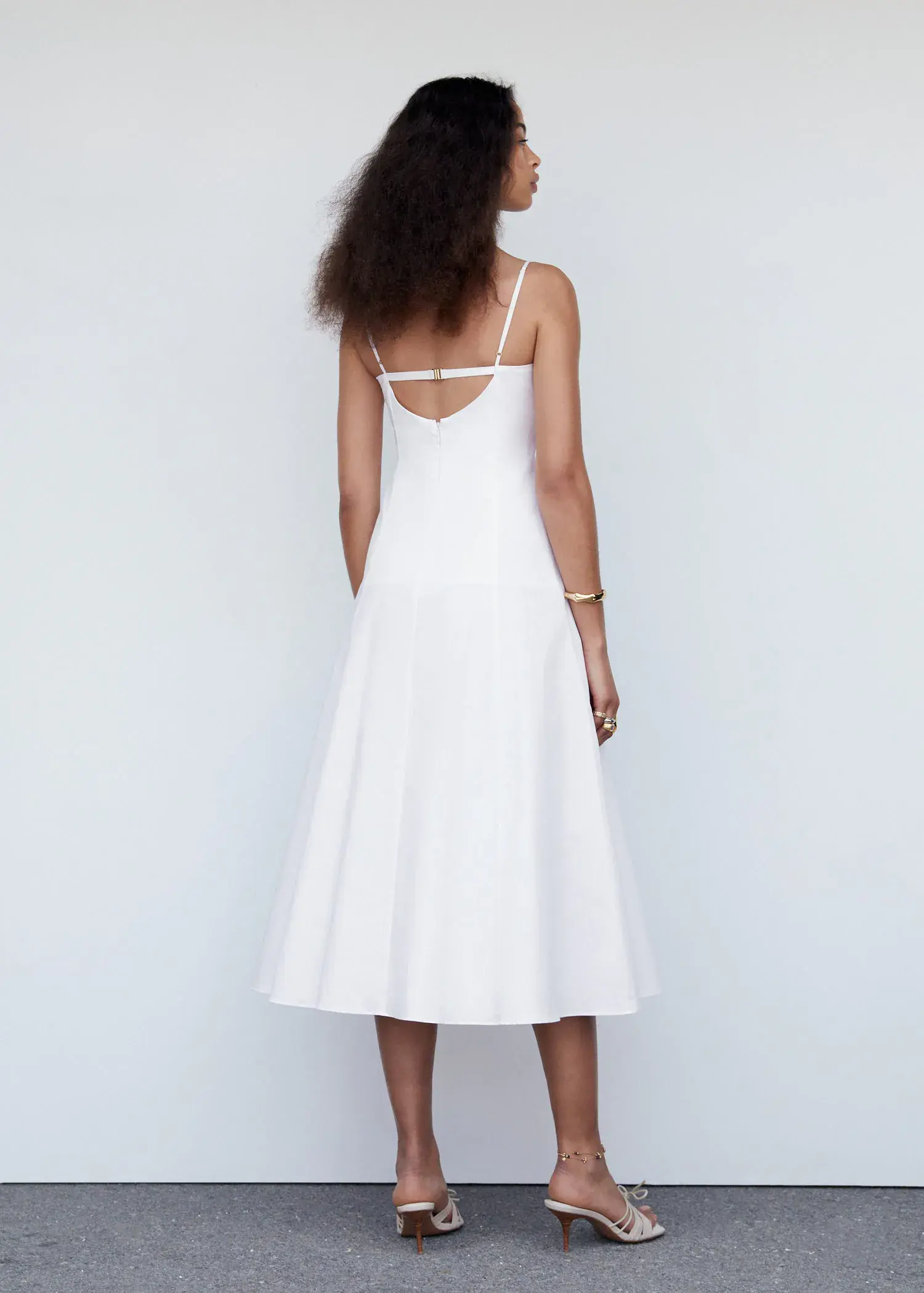 Mango Midi-dress with back detail. a woman wearing a white dress standing next to a white wall. 