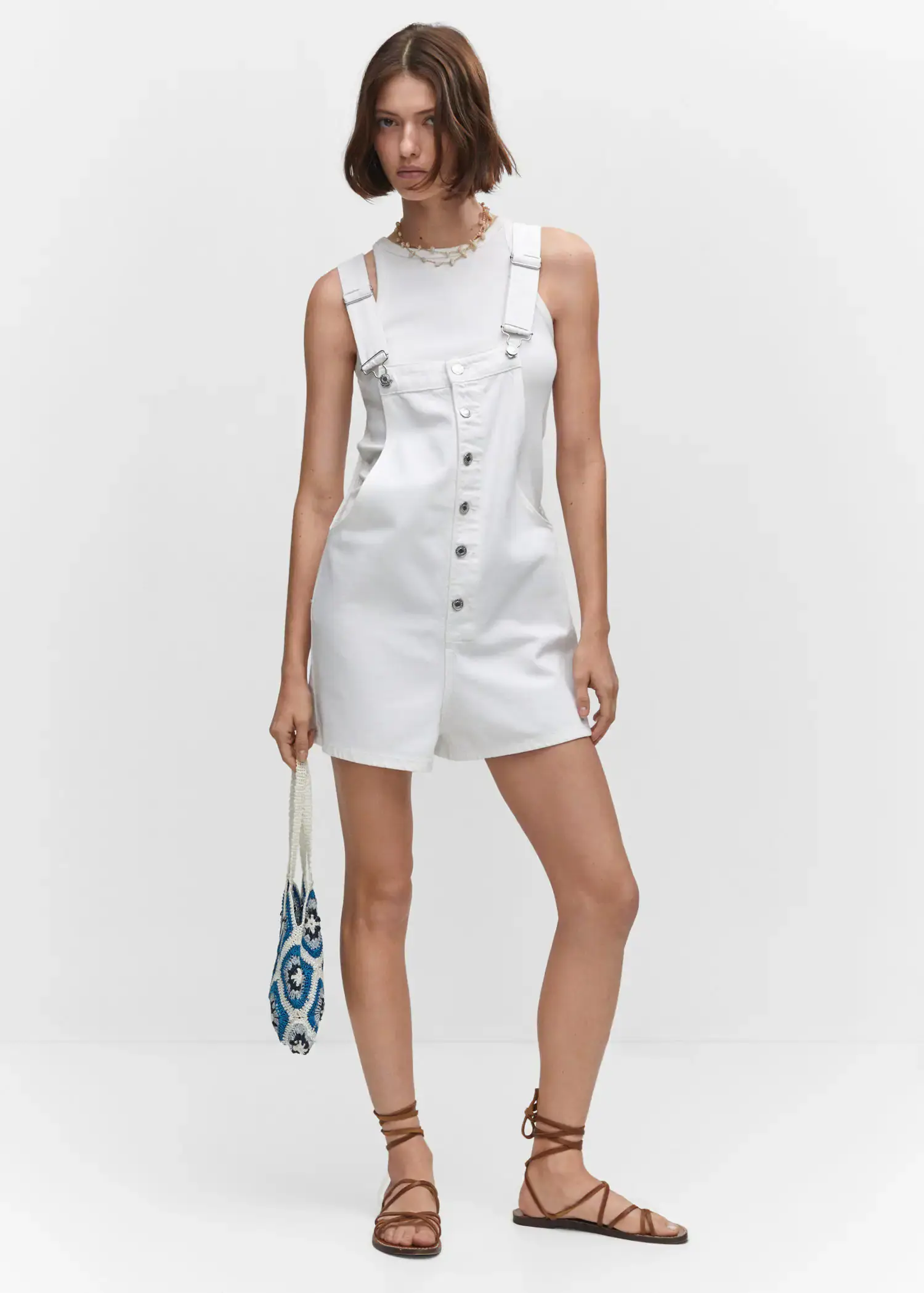Mango Denim button-down dungarees. a woman in a white dress holding a blue bag. 