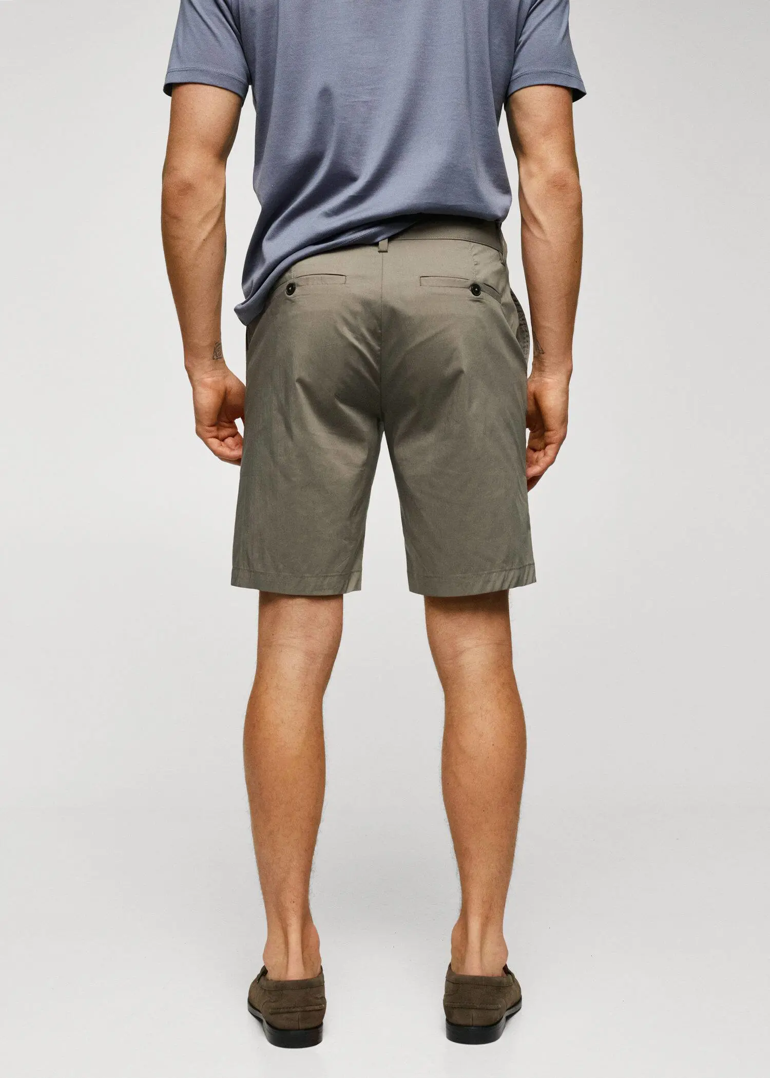 Mango Cotton pleated Bermuda shorts. a man is standing in front of a wall. 