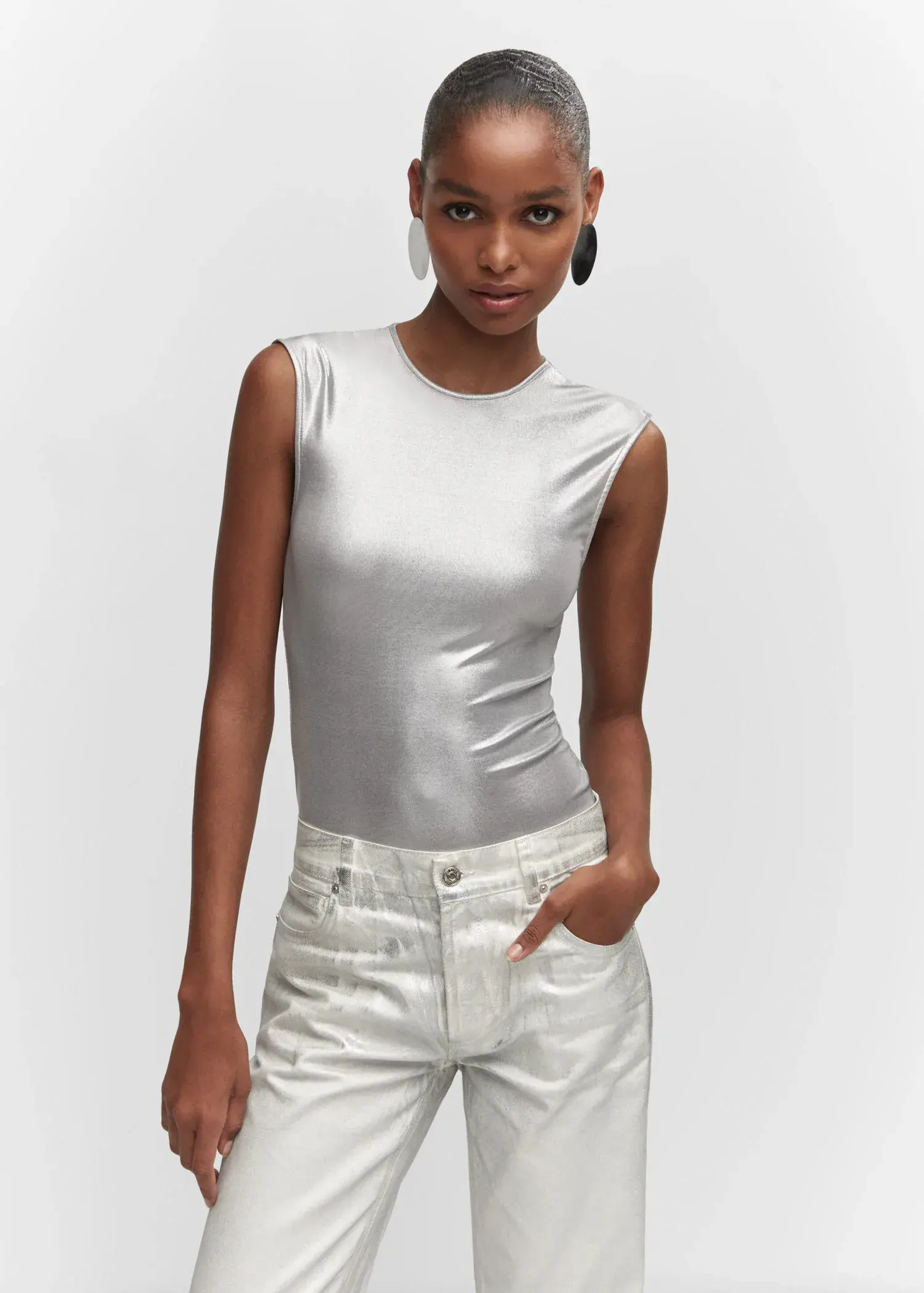 Mango Metallic bodysuit. a woman wearing white pants and a silver tank top. 
