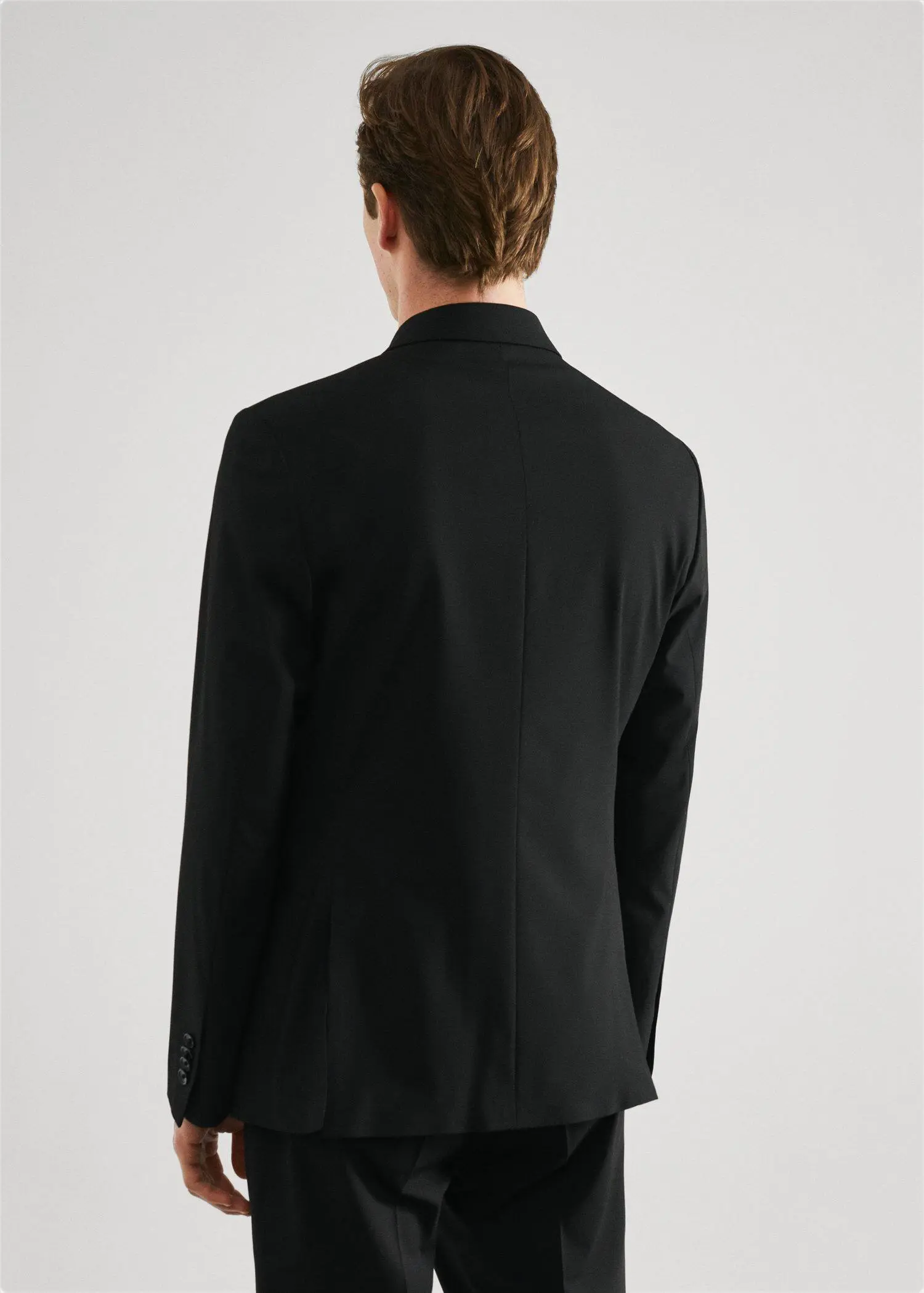 Mango Slim fit double-breasted suit blazer. a man wearing a black suit standing in front of a white wall. 