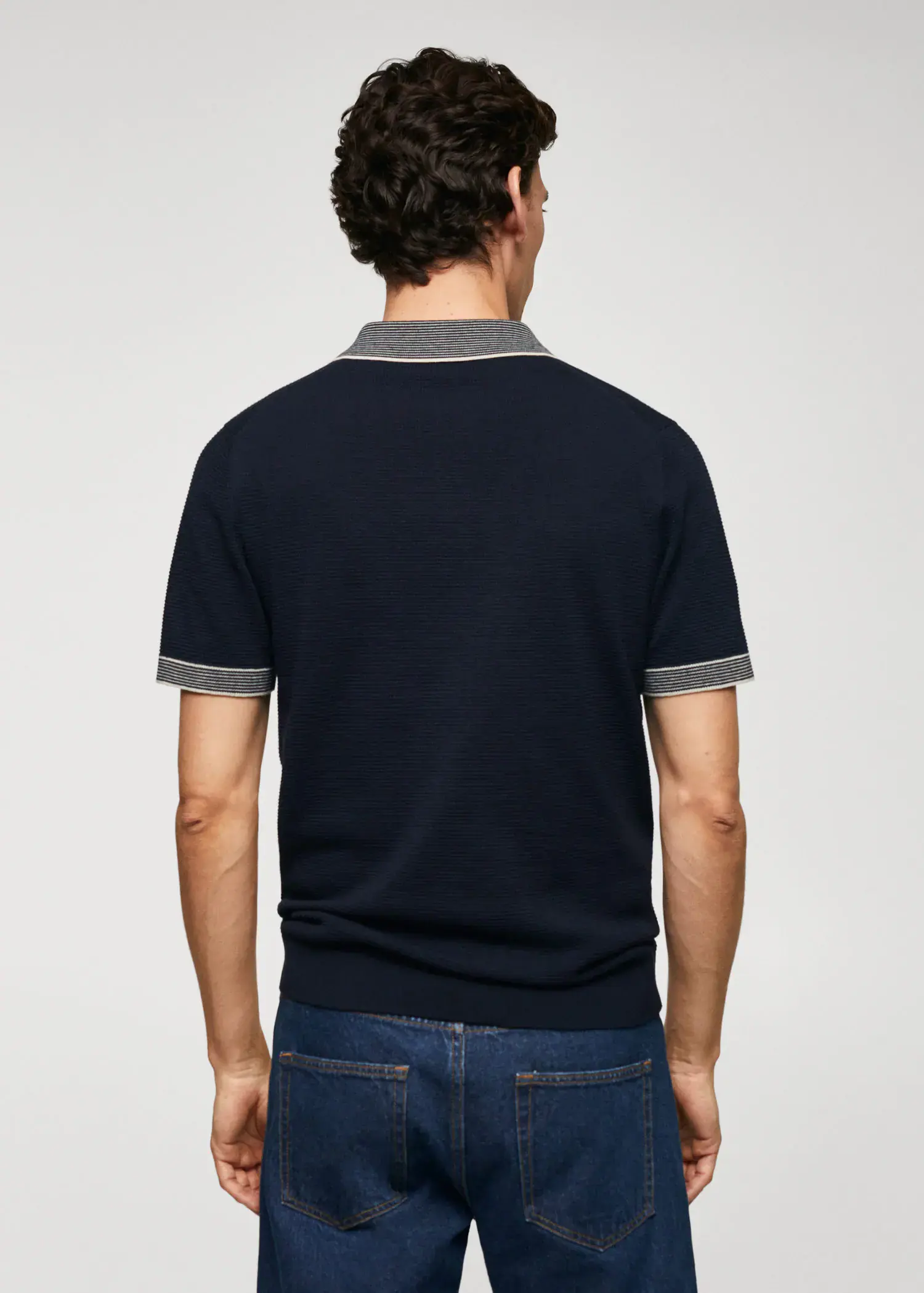 Mango Fine-knit polo shirt with zip. a man wearing a black polo shirt and blue jeans. 
