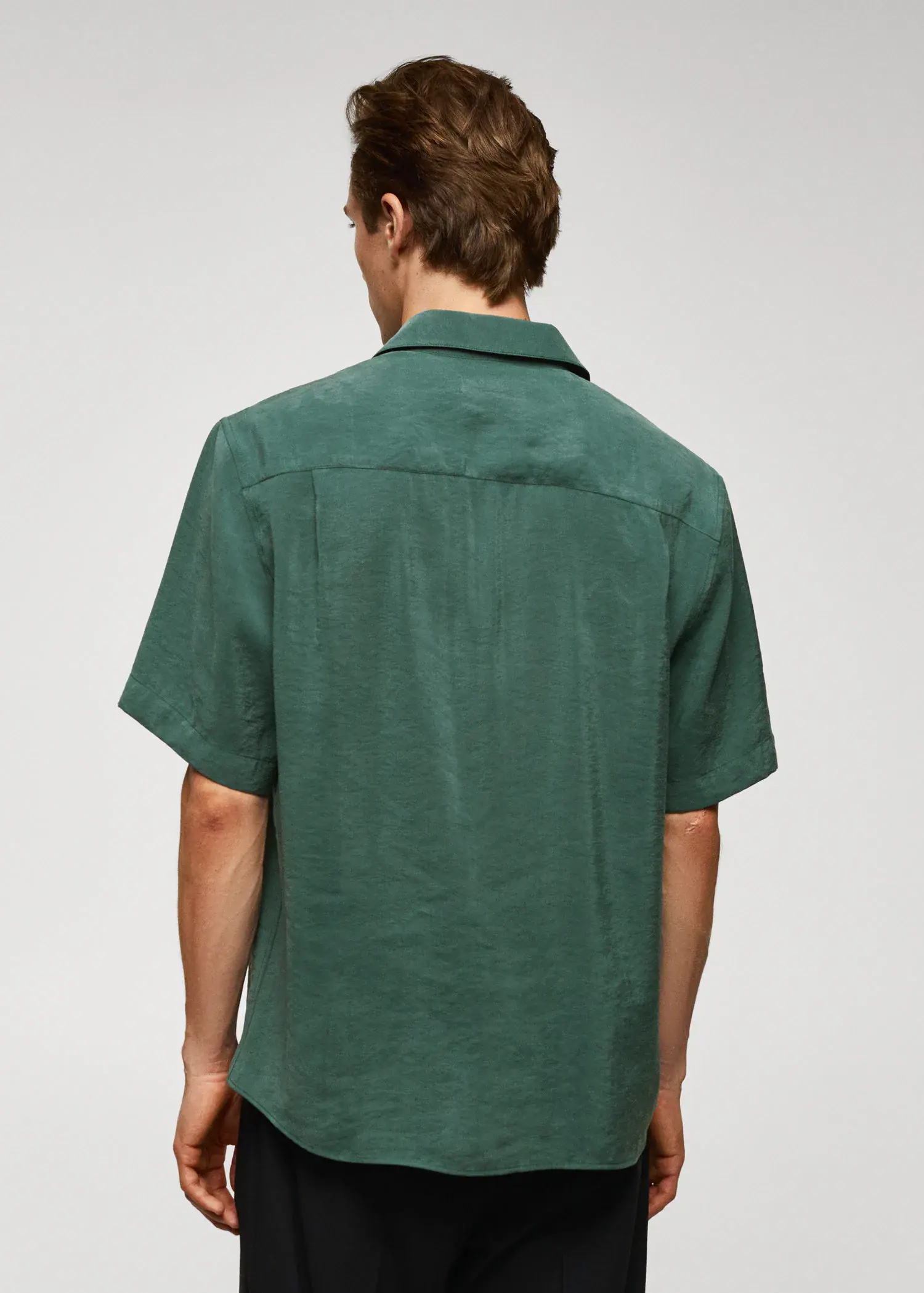 Mango Regular-fit short-sleeved shirt. a man in a green shirt is standing in front of a white wall. 
