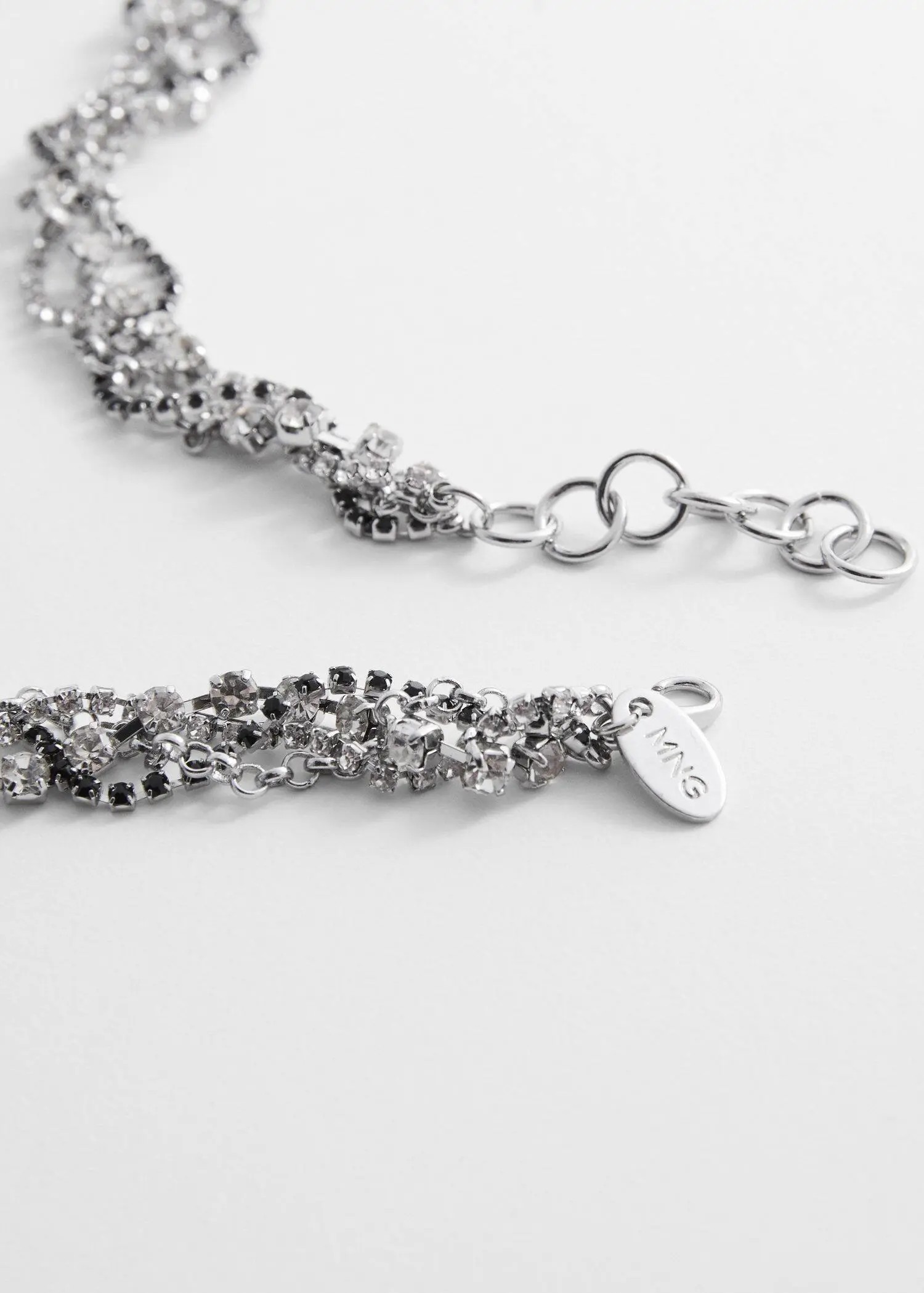 Mango Strass intertwined necklace. a close-up of a silver necklace with a tag. 
