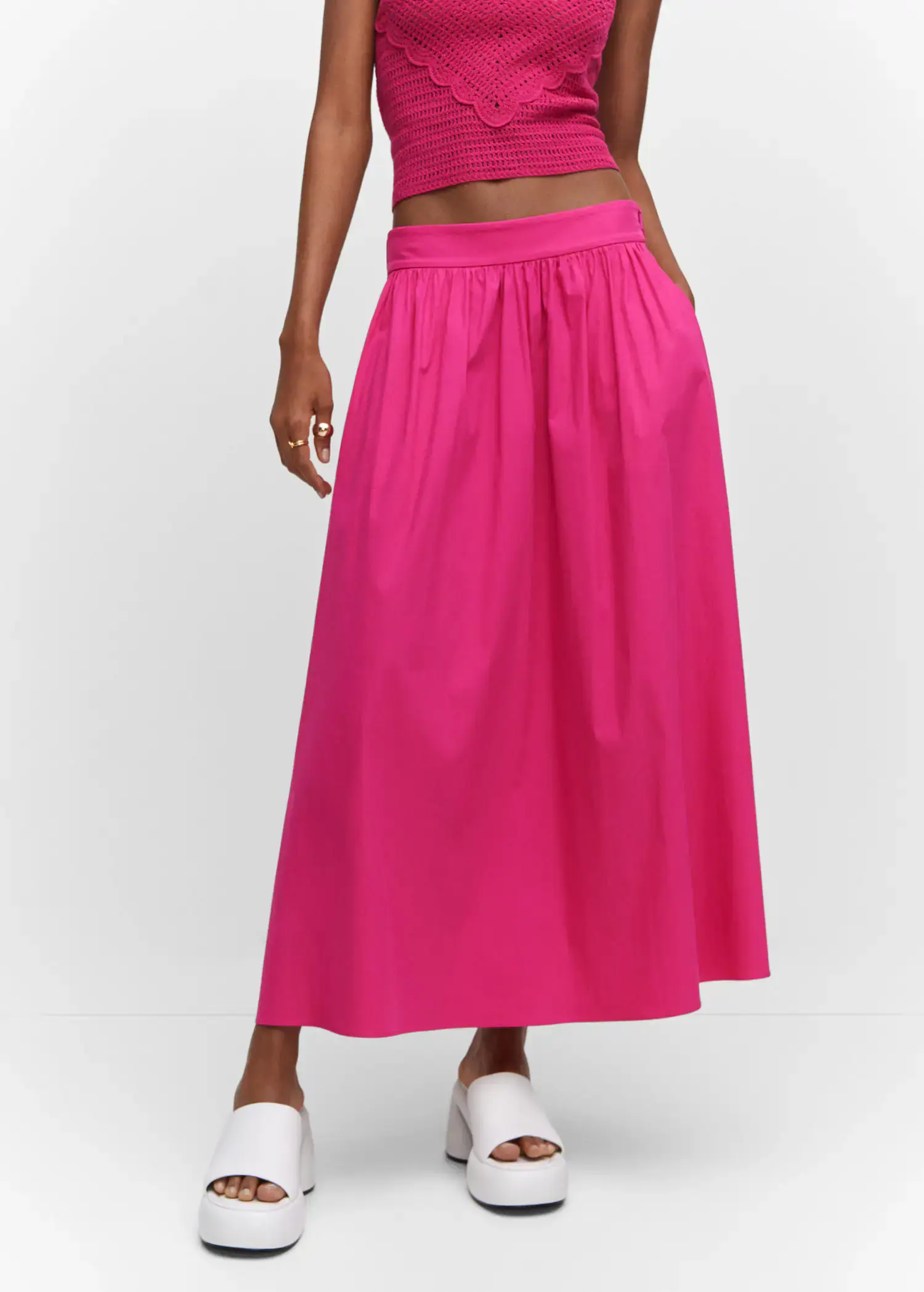 Mango Pleat detail long skirt. a woman wearing a long pink skirt and white sneakers. 