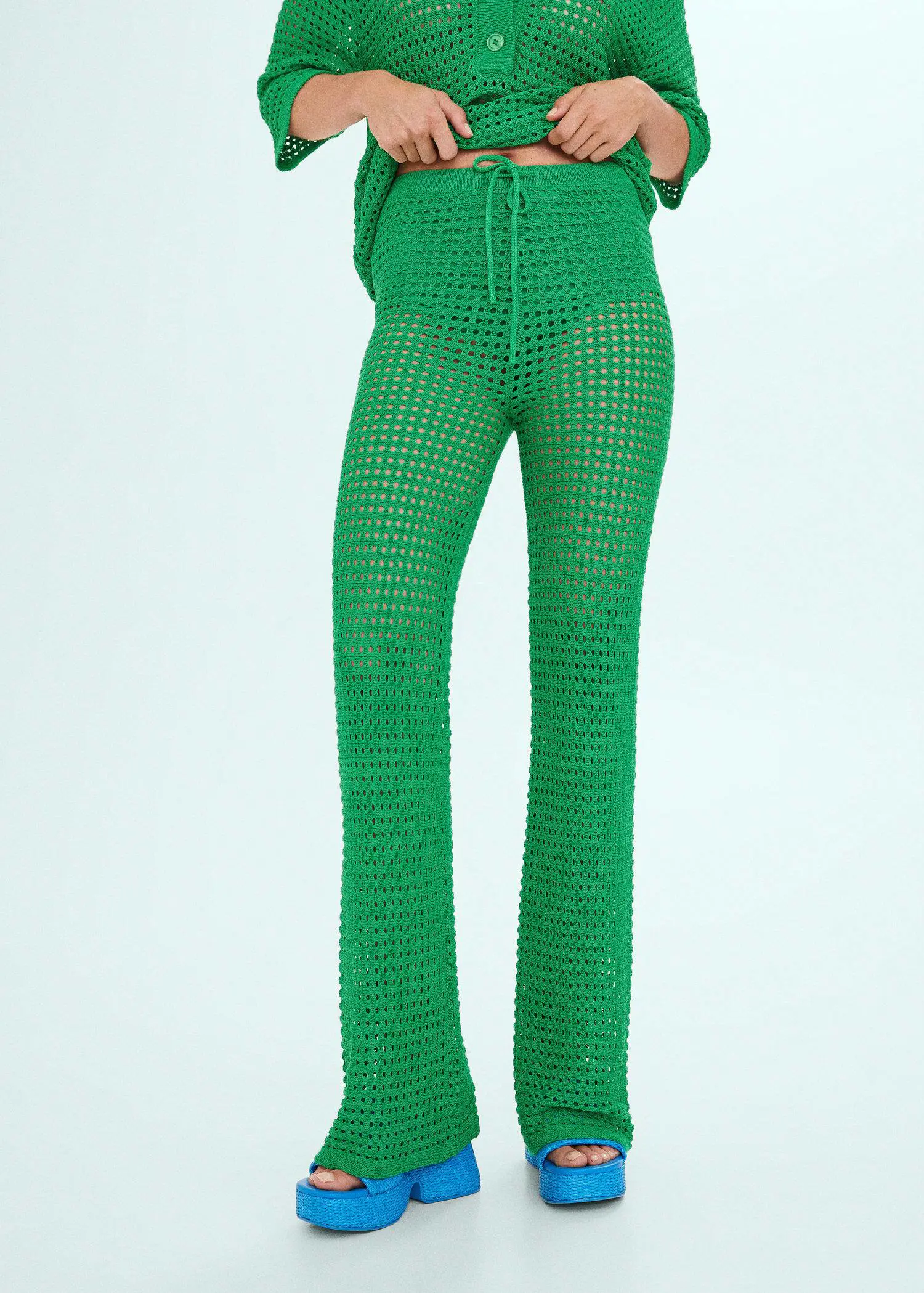 Mango Openwork knit trousers. a person wearing a green outfit standing up. 