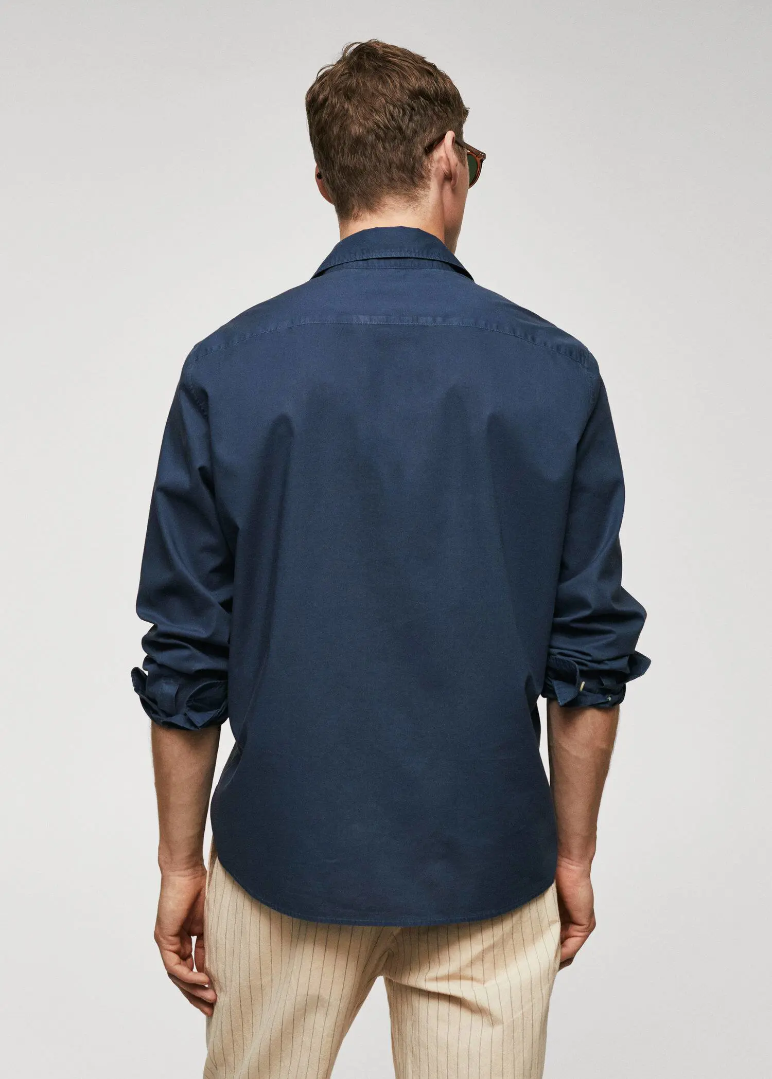 Mango Regular-fit cotton voile shirt. a man in a blue shirt is standing in front of a white wall. 