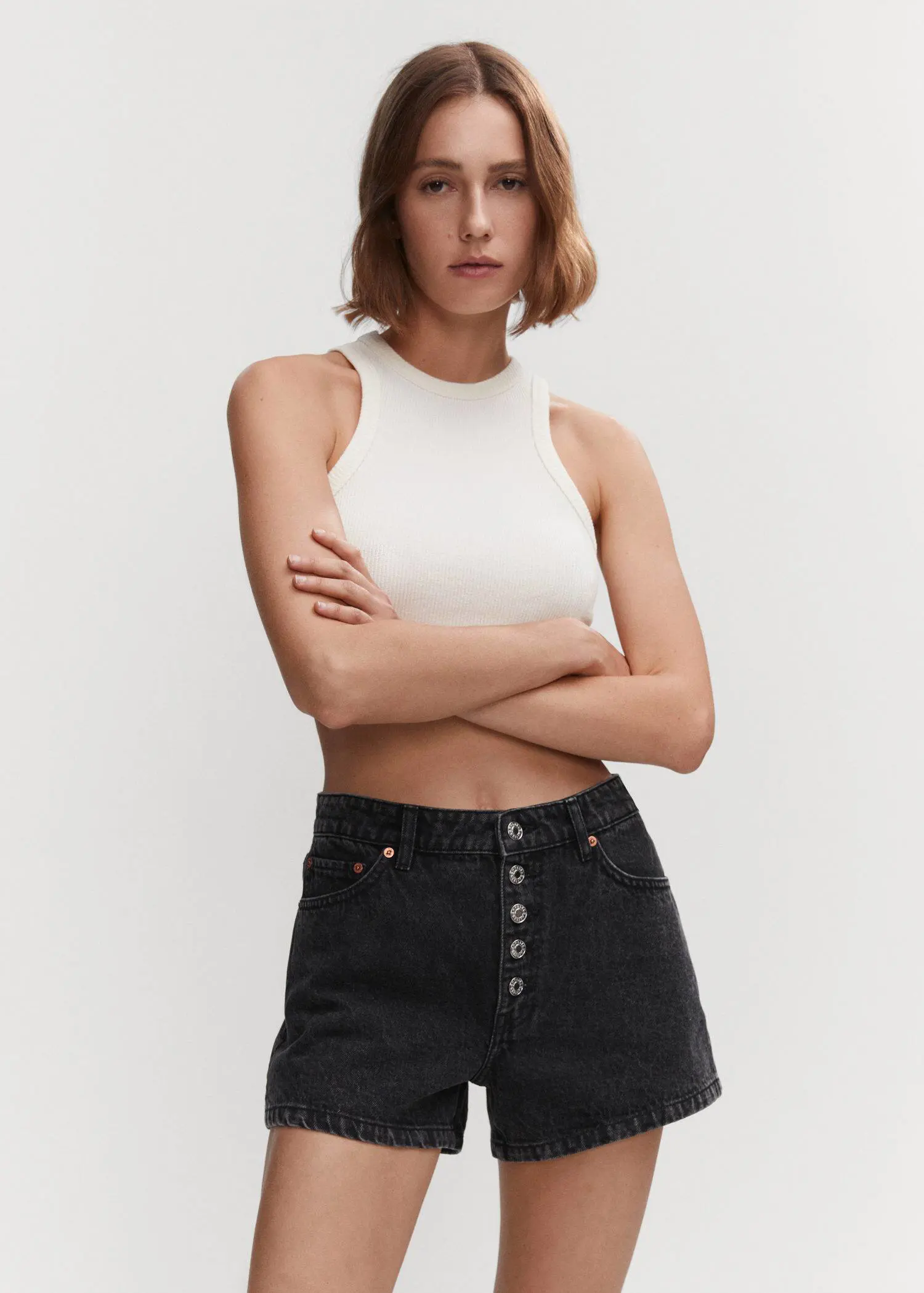 Mango Denim shorts with buttons. a woman in a white crop top and black shorts. 