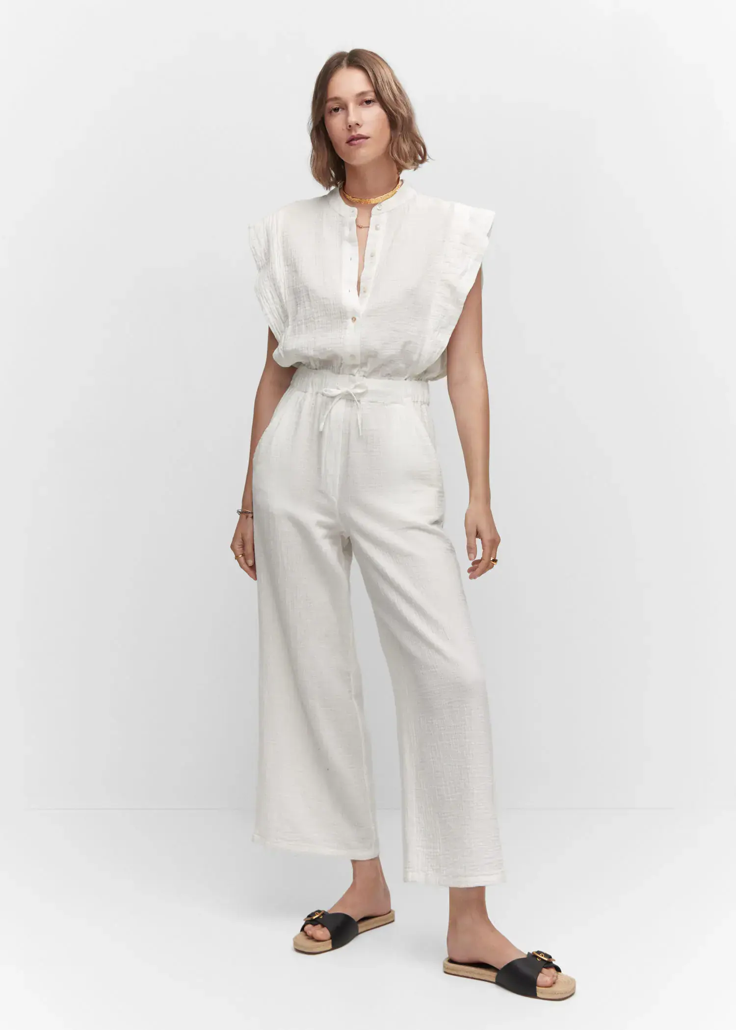 Mango Textured jumpsuit with button. a woman wearing a white jumpsuit standing in front of a white wall. 