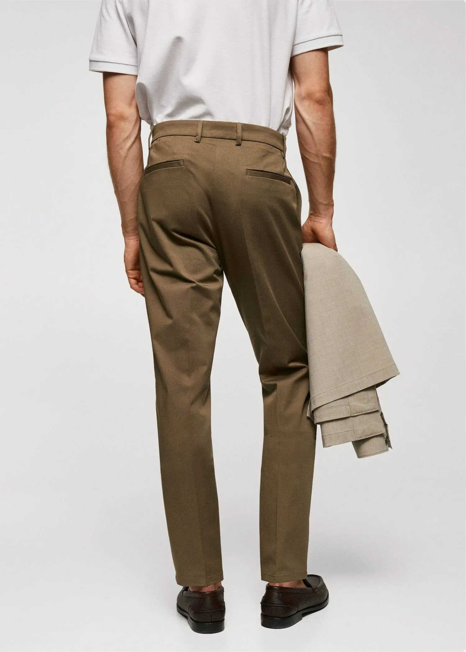 Mango Slim fit chino trousers. a man in a tan suit is holding his jacket. 