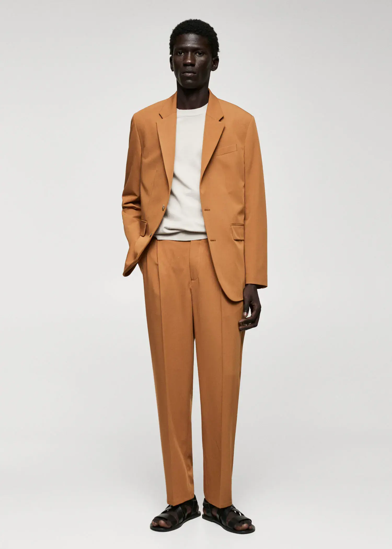 Mango Regular-fit suit trousers with pleats. a man in a suit standing in front of a white wall. 