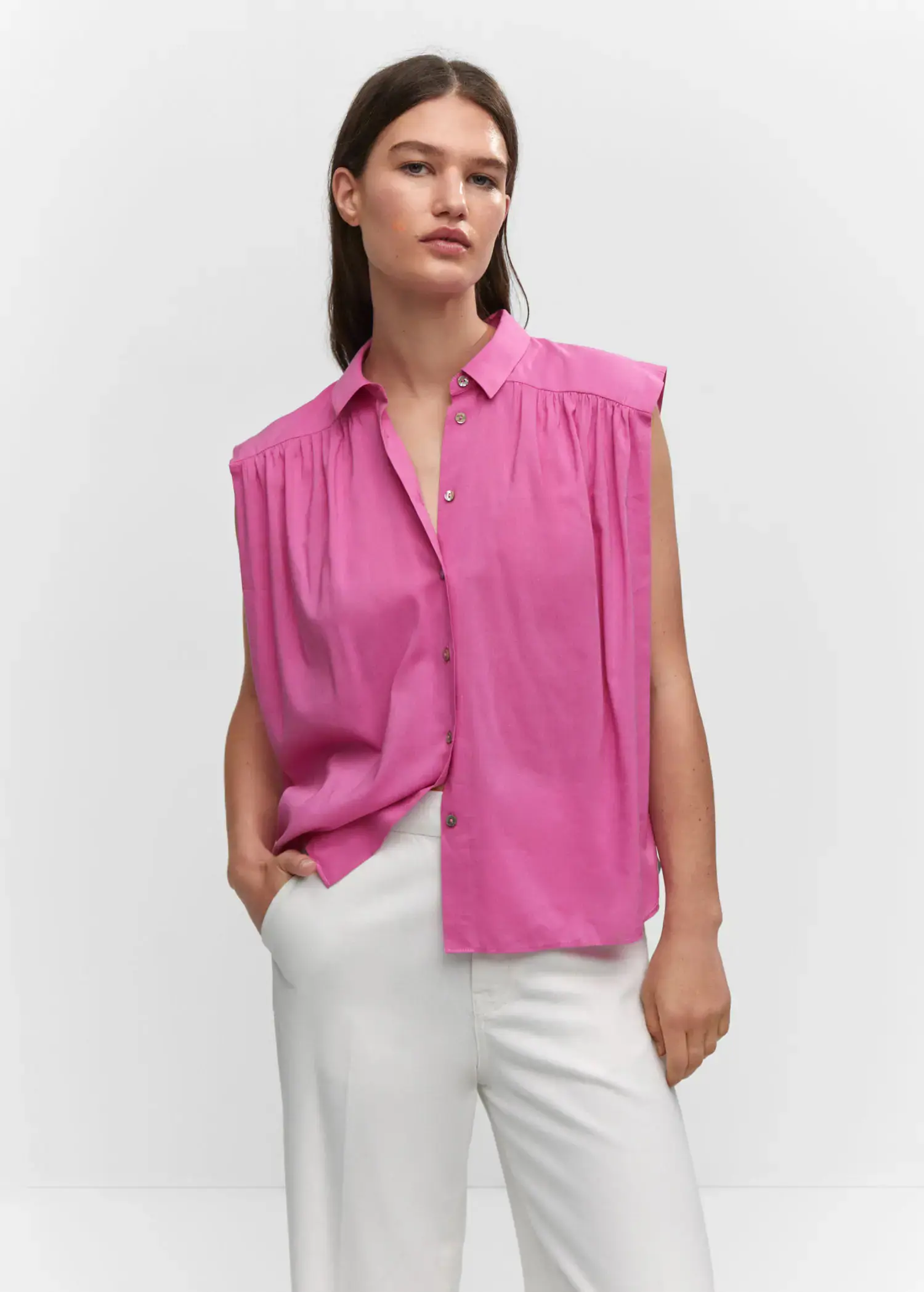 Mango Sleeveless button-down shirt. a woman wearing a pink shirt and white pants. 