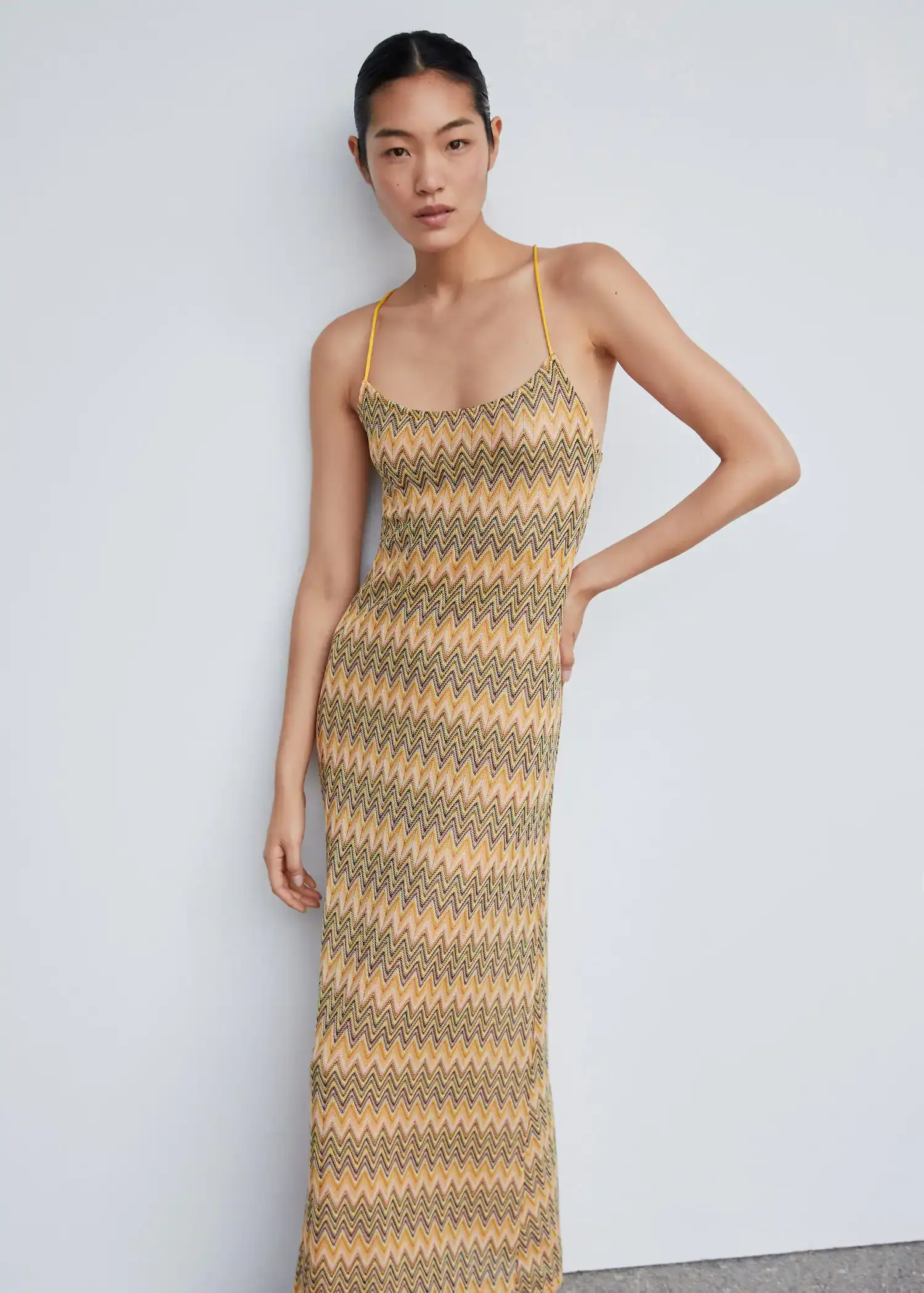 Mango Geometric pattern dress. a woman wearing a long dress leaning against a wall. 