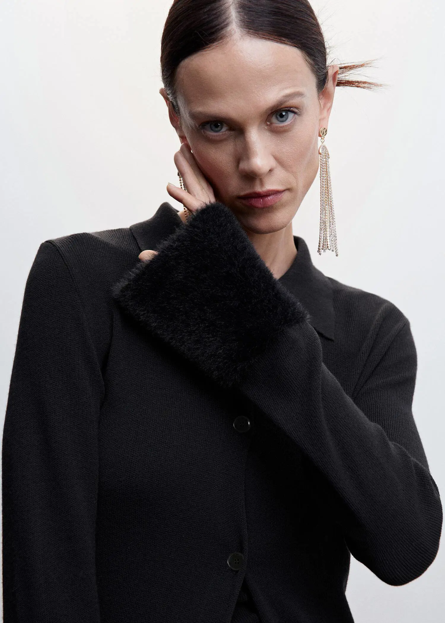 Mango Cardigan with fur-effect detail. a woman in a black shirt holding her hand up to her face. 