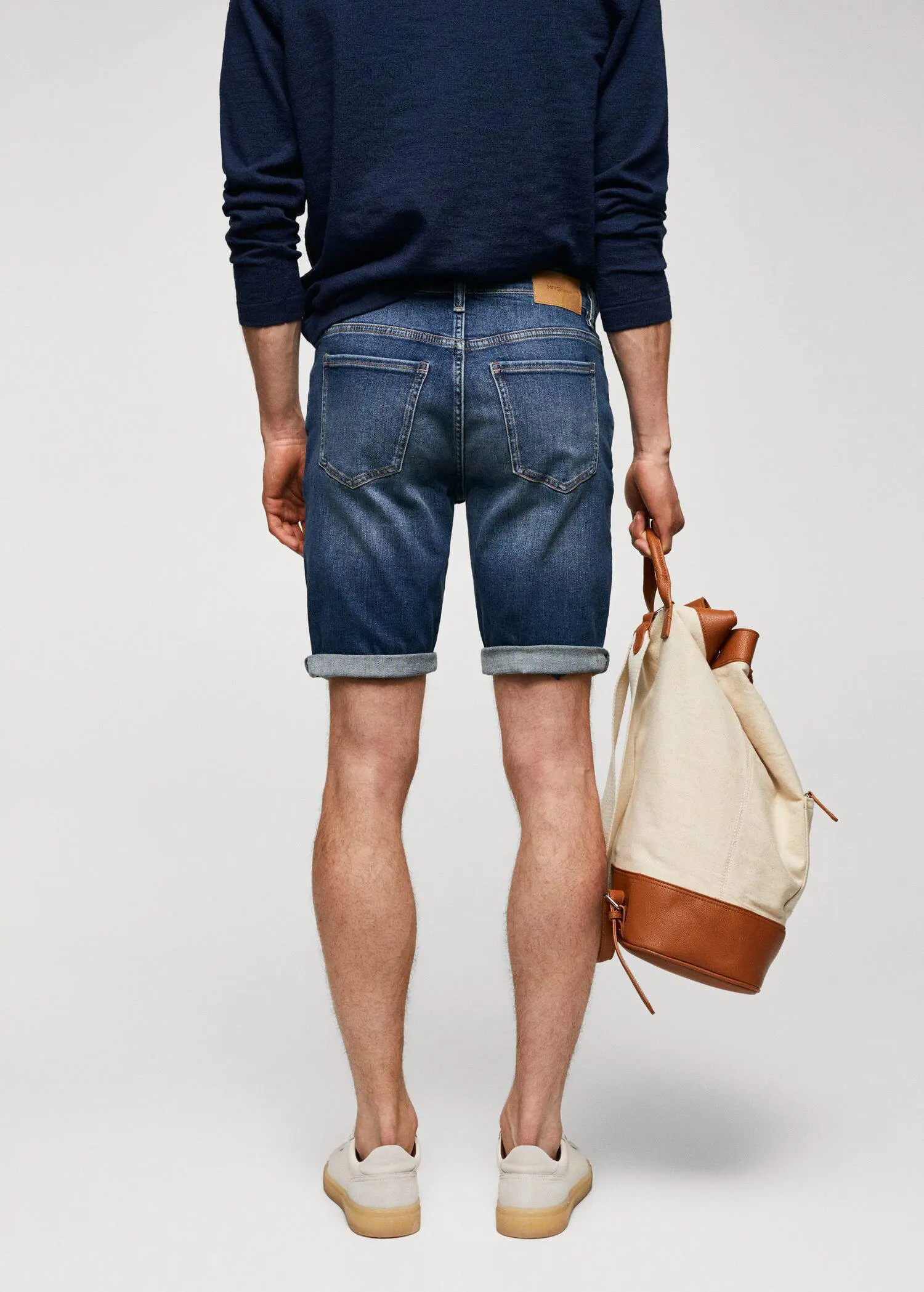 Mango Slim-fit denim bermuda shorts. a man holding a bag while standing on his back legs. 