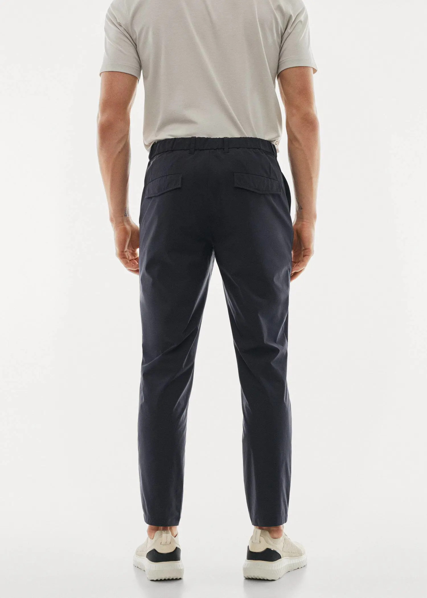Mango Water-repellent technical trousers. a man standing in front of a white wall. 