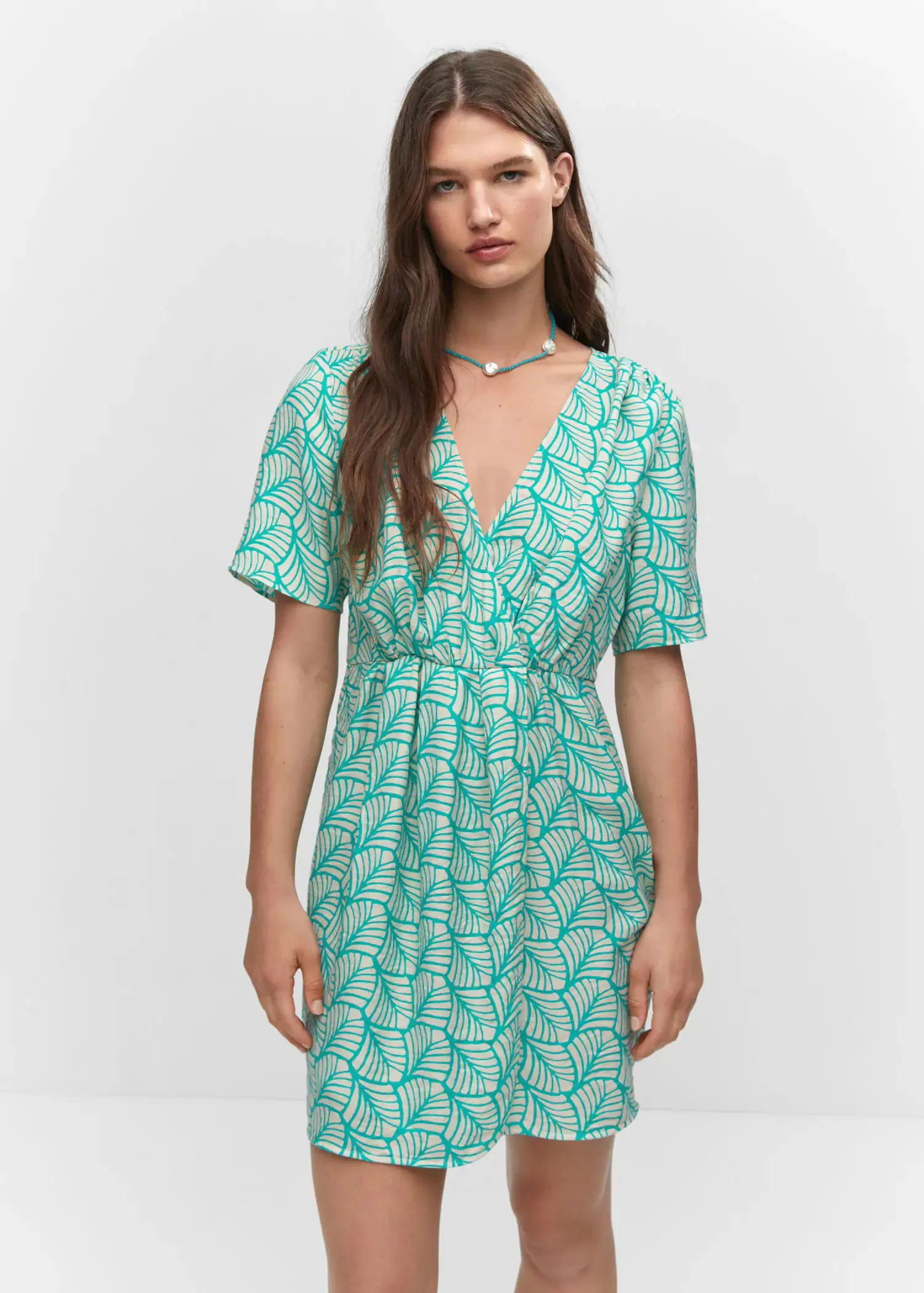 Mango Short printed wrap dress. a woman wearing a green dress standing in front of a white wall. 