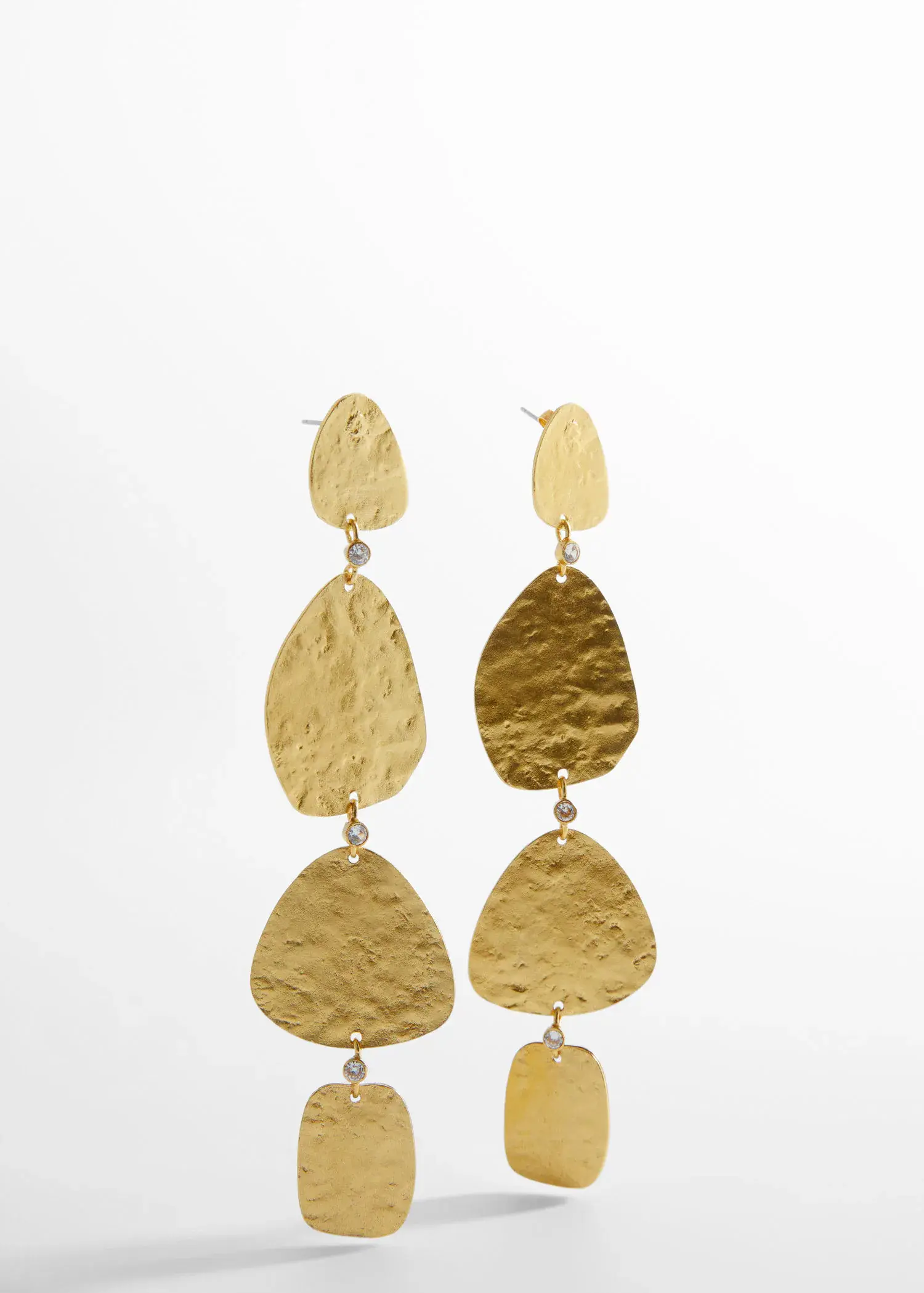 Mango Textured earrings. a pair of gold earrings hanging on a white wall. 
