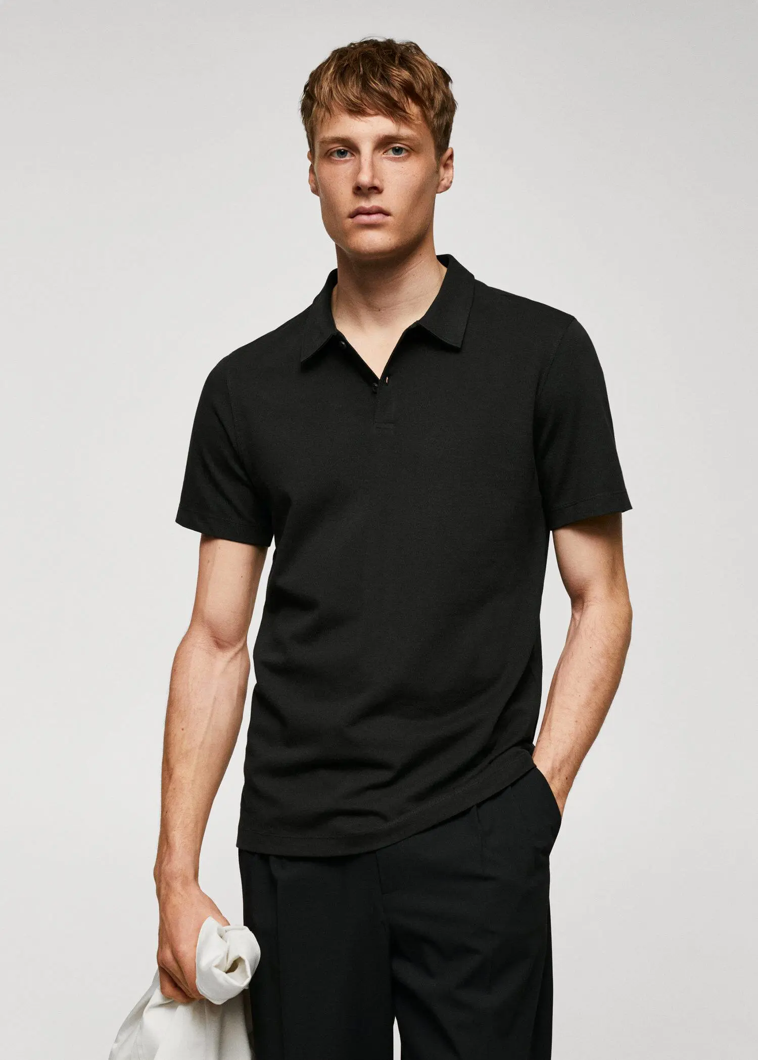 Mango Slim-fit textured cotton polo shirt. a man in a black polo shirt is posing for a picture. 