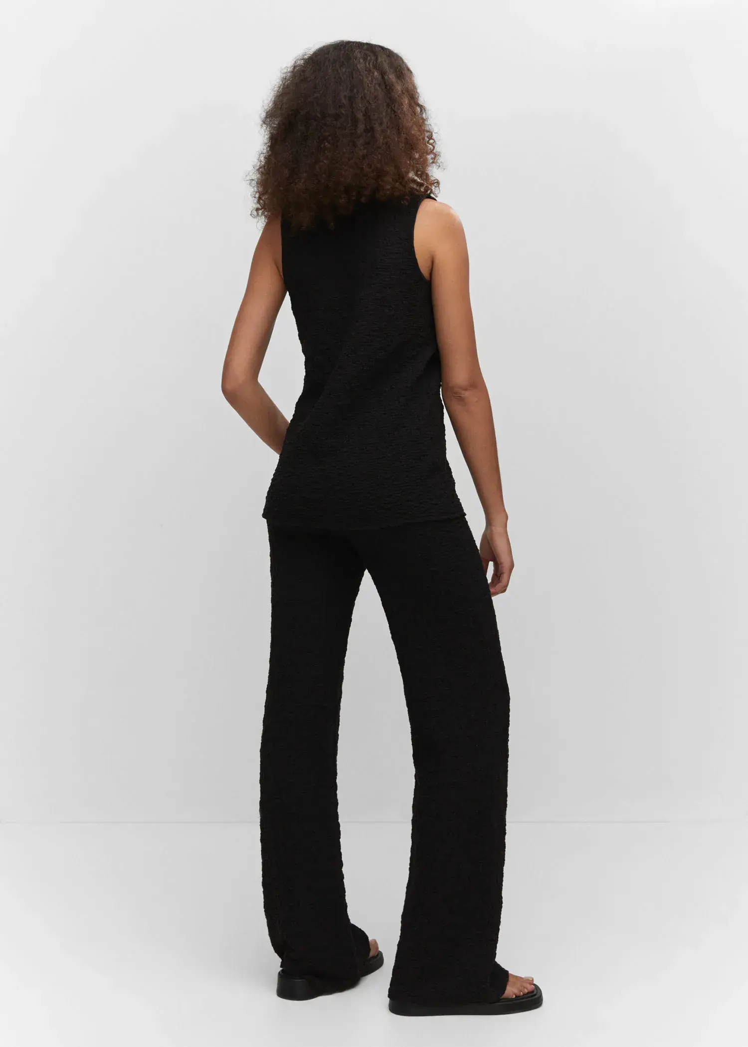 Mango Textured polo neck gilet. a woman wearing a black top and black pants. 