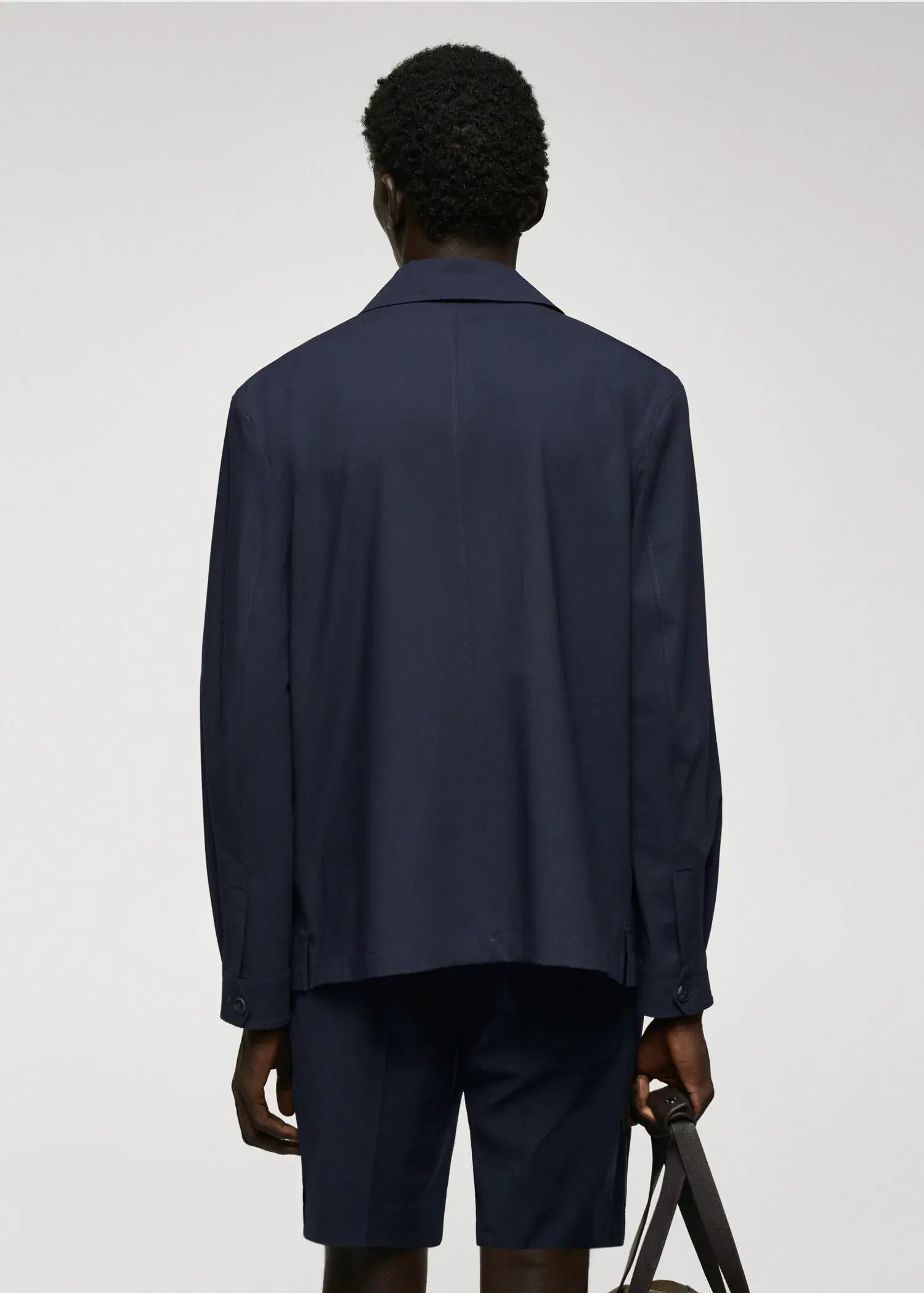 Mango Lightweight pocket jacket. a man wearing a dark blue shirt is standing. 