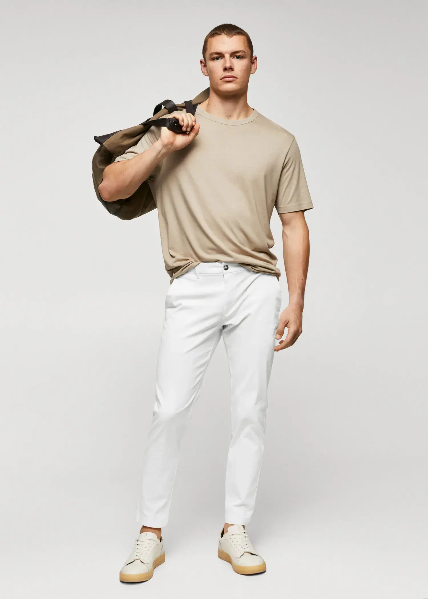 Mango Cotton tapered crop pants. a man holding onto a bag while wearing white pants. 