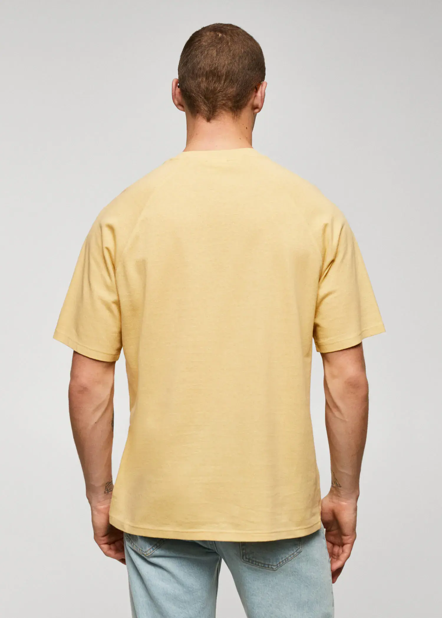 Mango Textured cotton-linen t-shirt. a man in a yellow shirt standing in front of a white wall. 