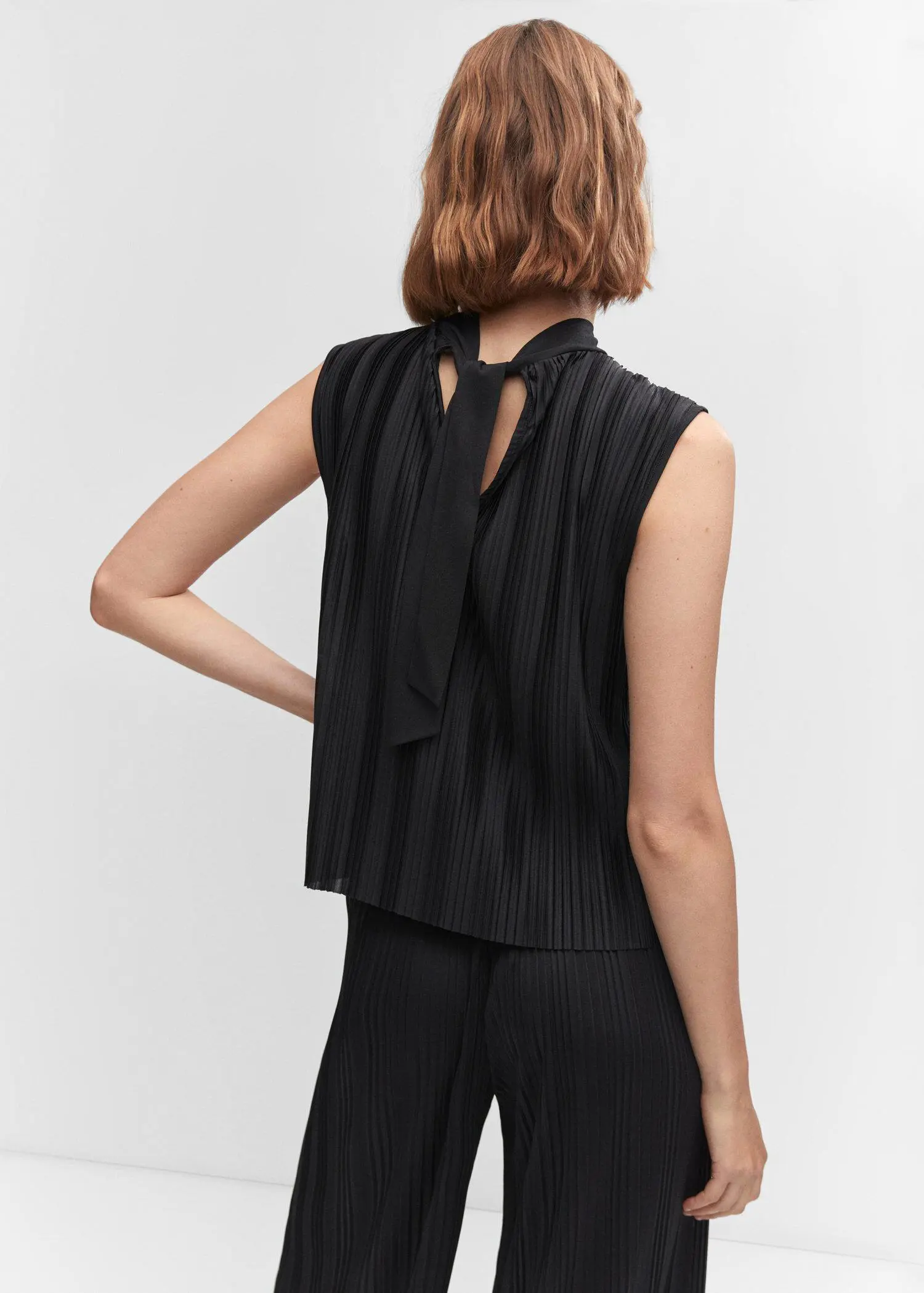 Mango Pleated bow top. a woman wearing a black top and black pants. 