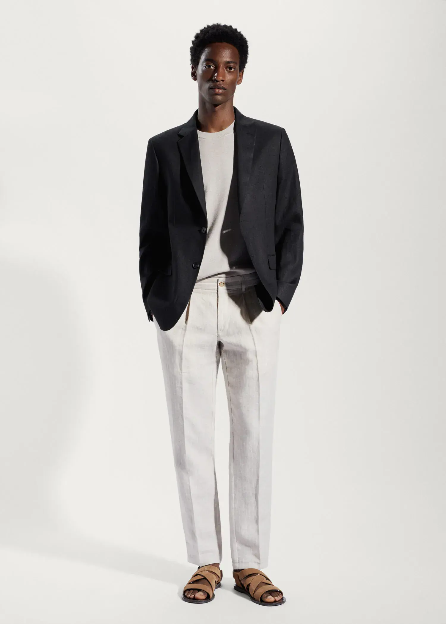 Mango 100% linen slim fit blazer. a man in a black jacket and white pants. 