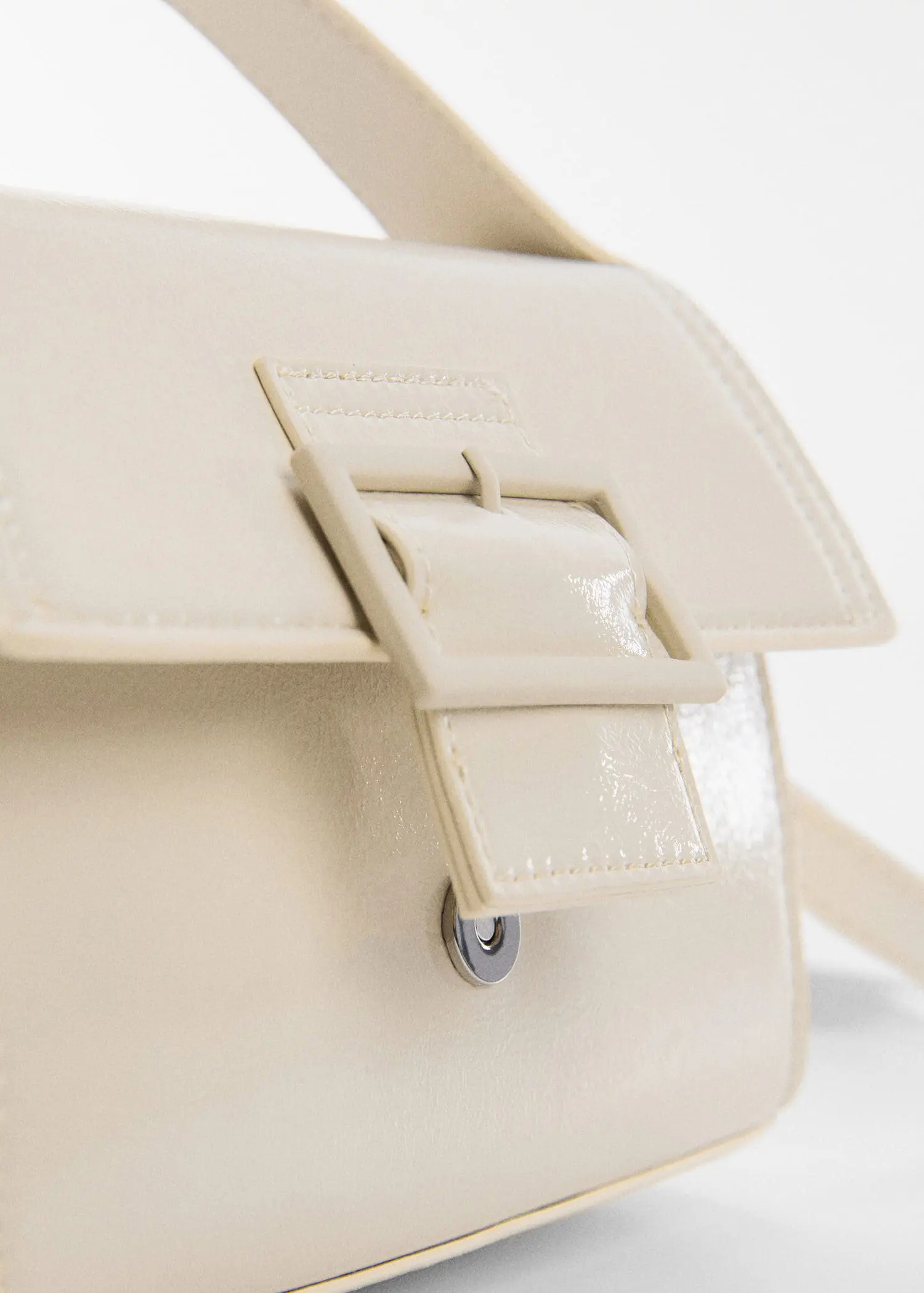 Mango Buckled flap bag. a close-up view of the buckle of a white purse. 