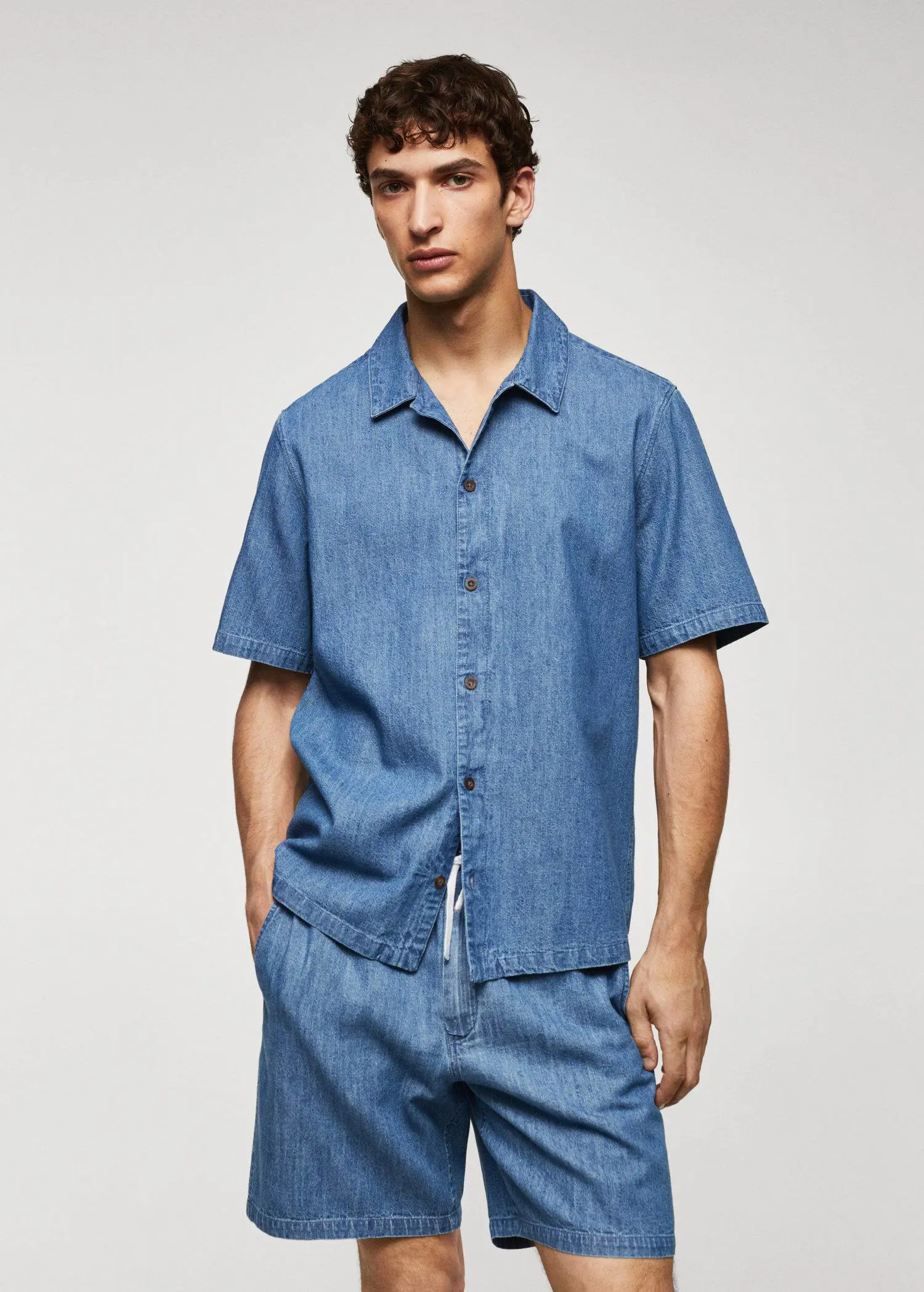 Mango 100% cotton chambray shirt. a man wearing a blue shirt and shorts. 