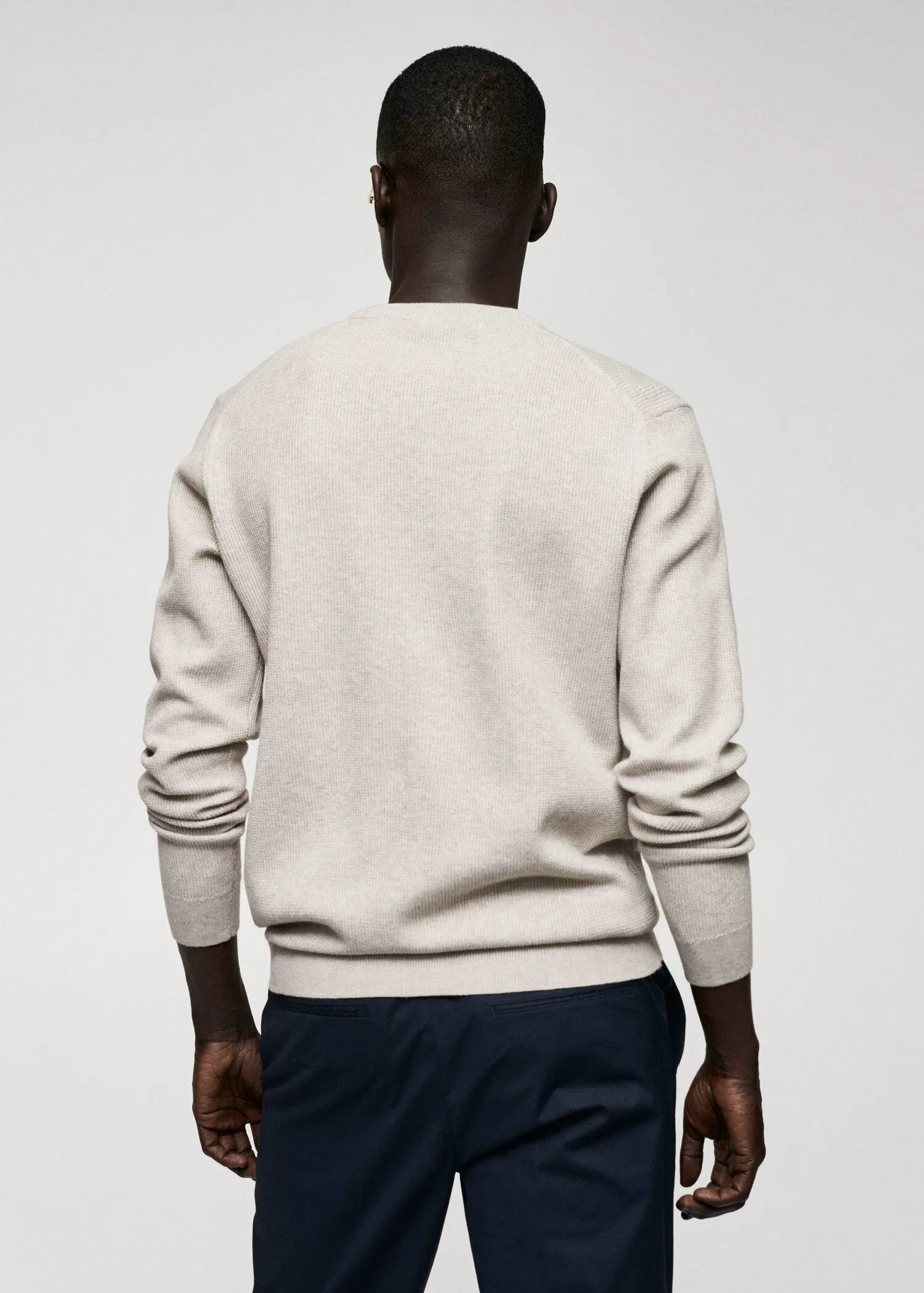 Mango Structured cotton sweater. a man wearing a white sweater standing in front of a white wall. 