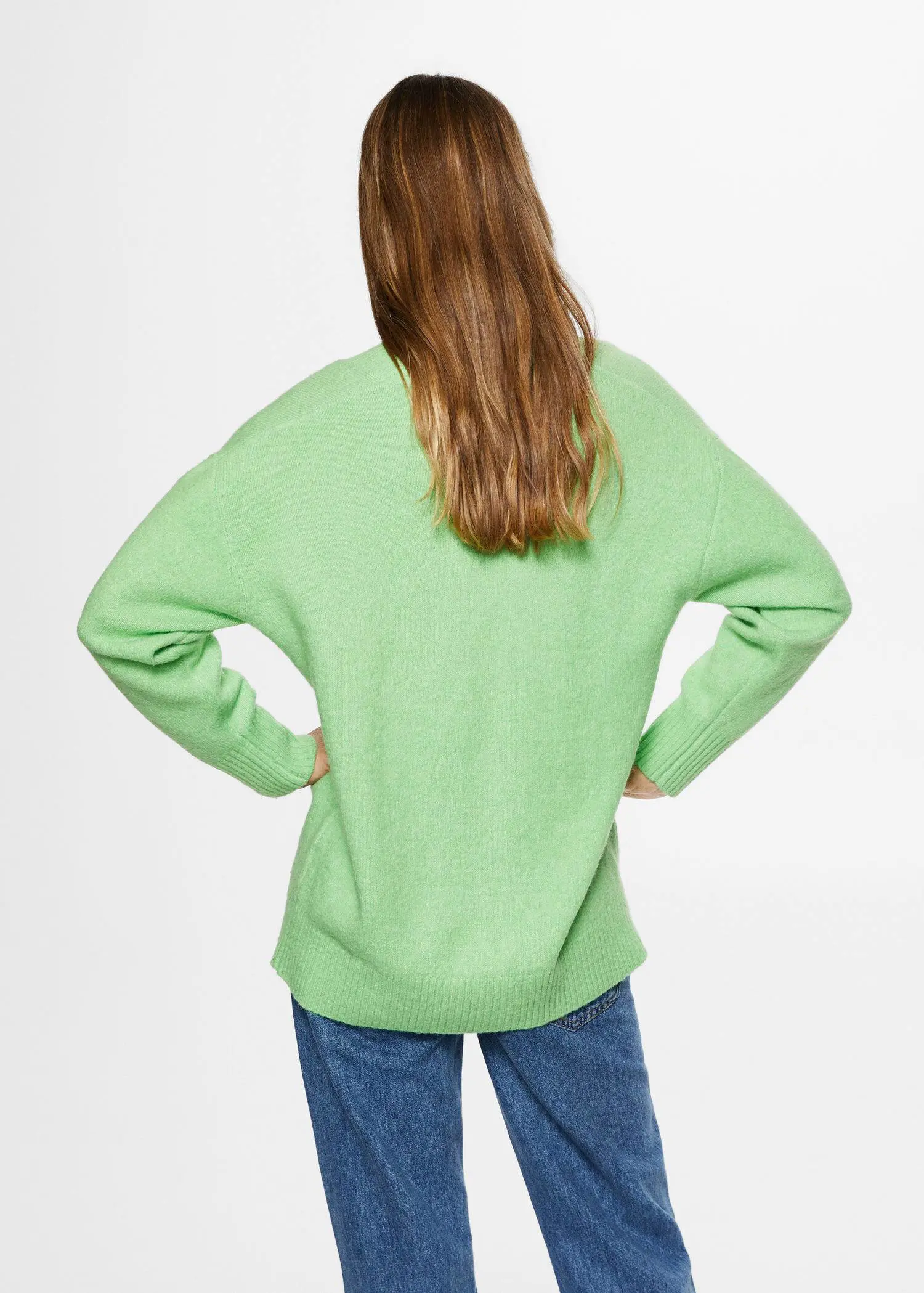 Mango V-neck sweater. a woman standing with her hands on her hips. 
