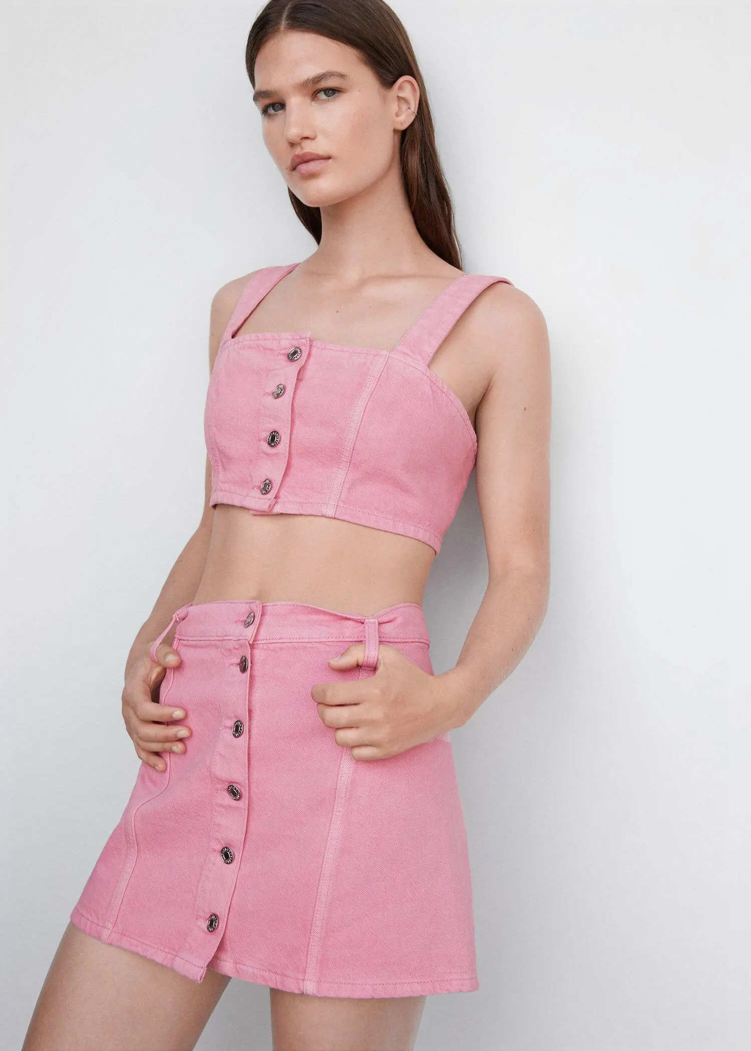 Mango Denim crop top. a woman wearing a pink outfit standing next to a wall. 