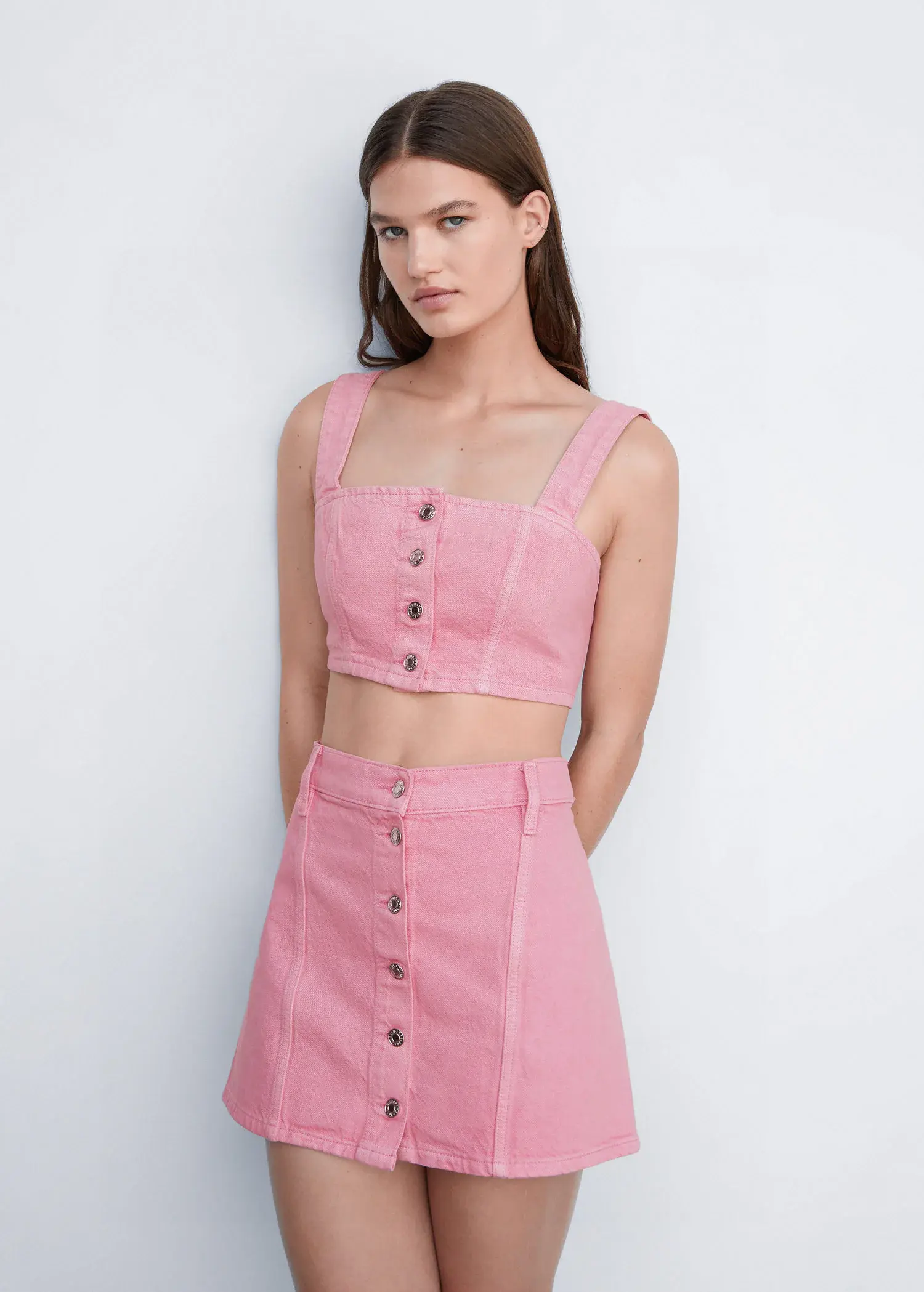 Mango Denim mini-skirt with buttons. a woman wearing a pink two-piece outfit. 