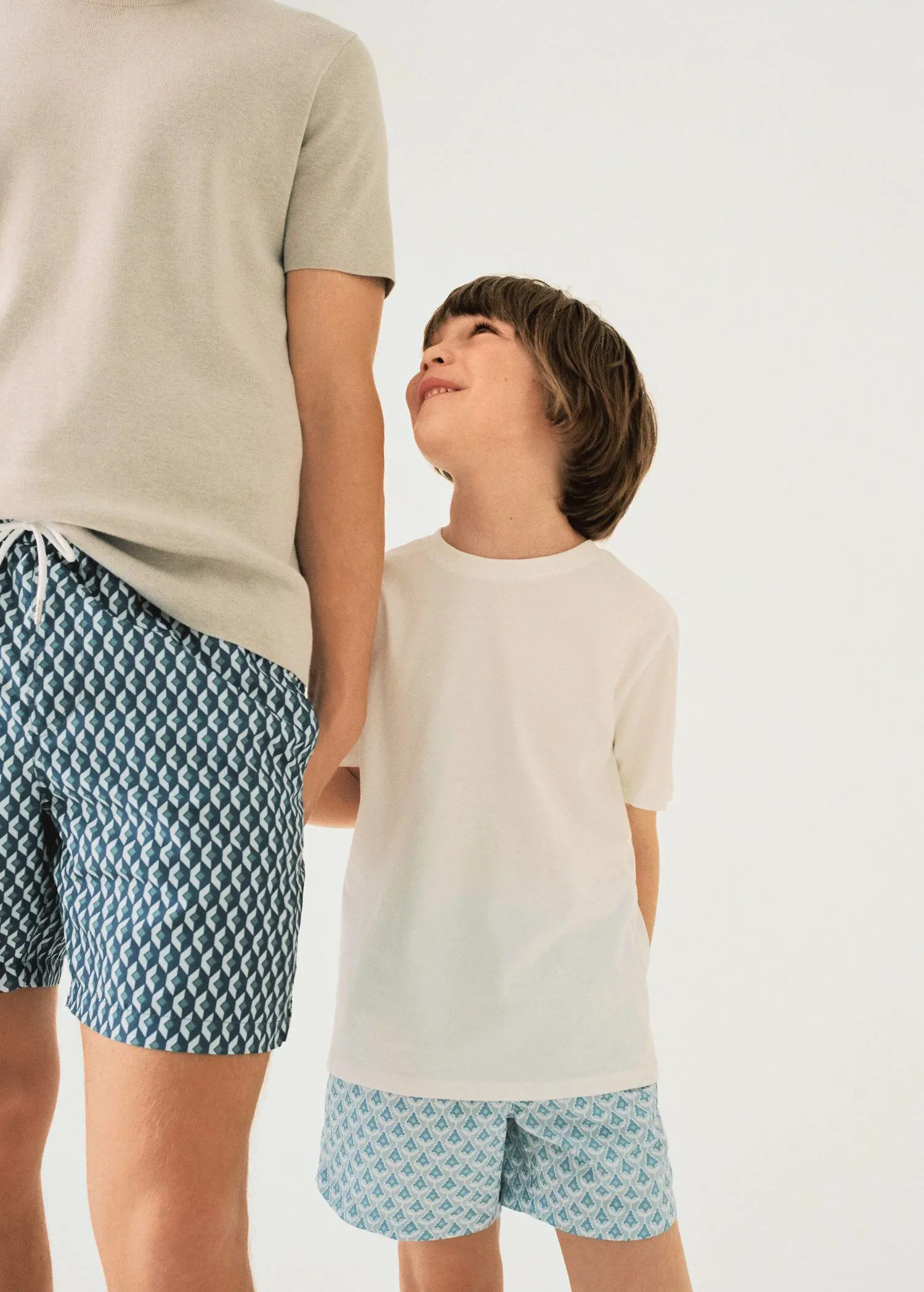 Mango KIDS/ Printed swimsuit. a man standing next to a boy with his mouth wide open. 
