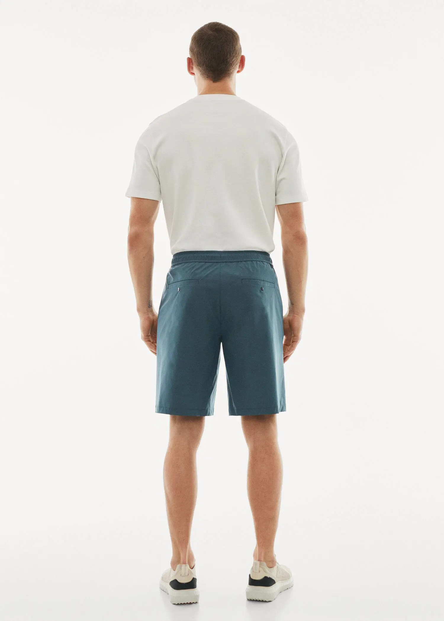 Mango Water-repellent technical bermuda shorts. a man standing in front of a white wall. 