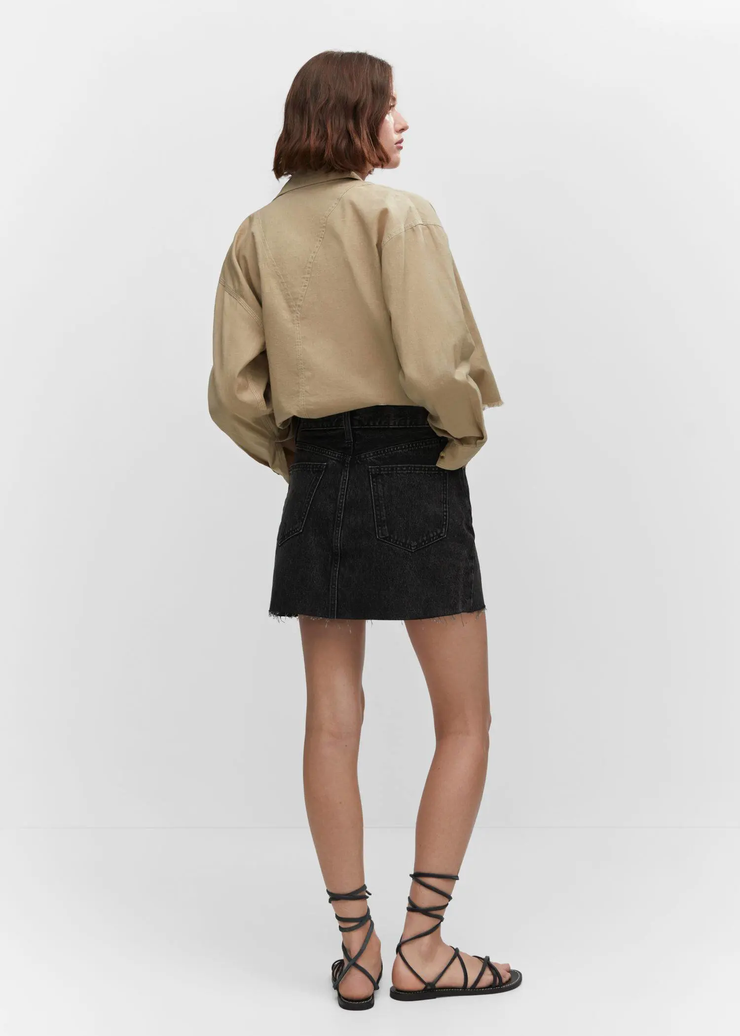 Mango Denim mini-skirt. a woman wearing a black skirt and a tan jacket. 