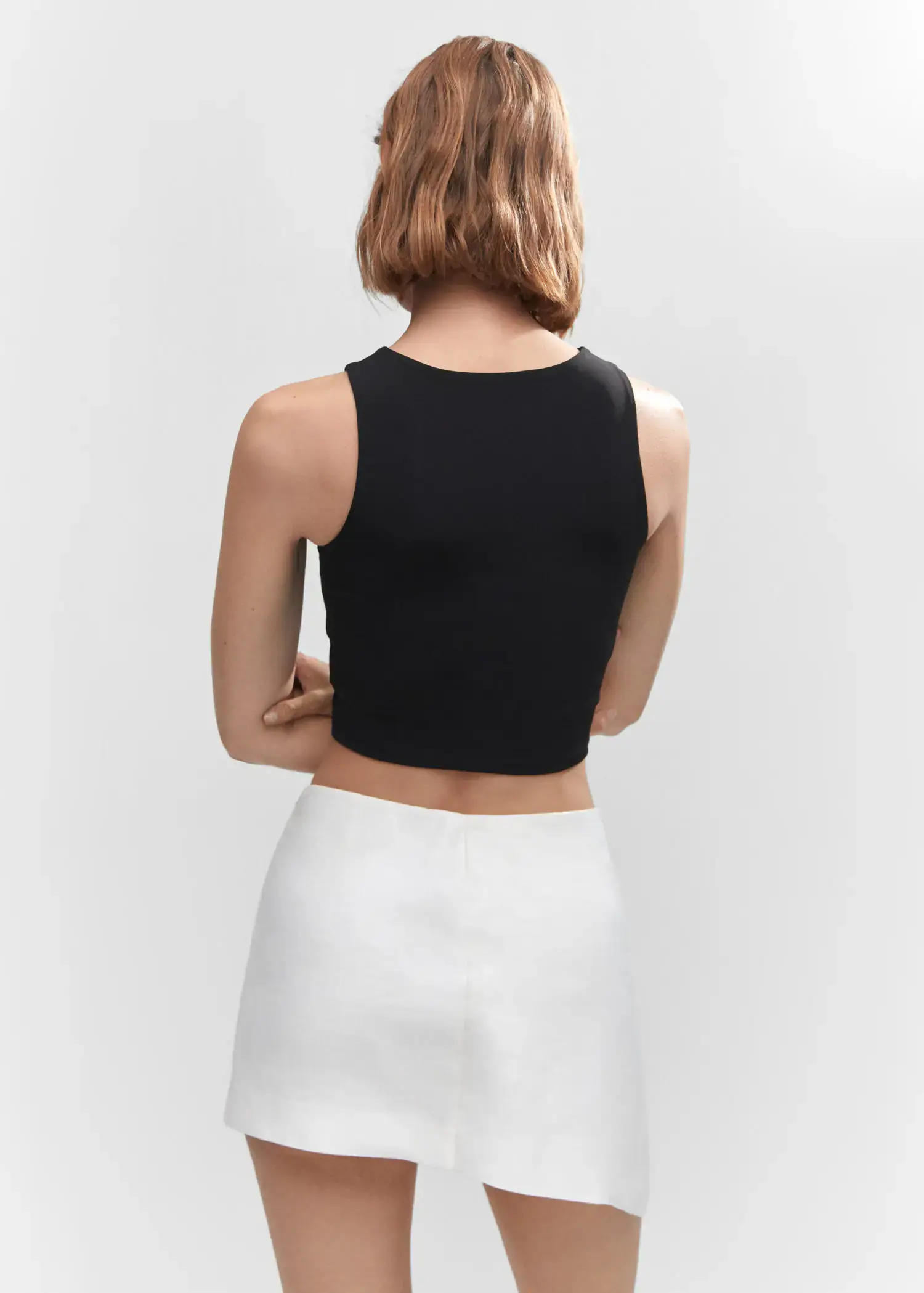 Mango Crop top halter neck. a woman wearing a black top and white skirt. 