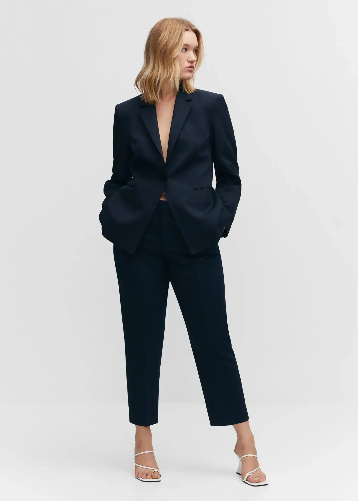 Mango Straight suit trousers. a woman wearing a black suit standing in front of a white wall. 