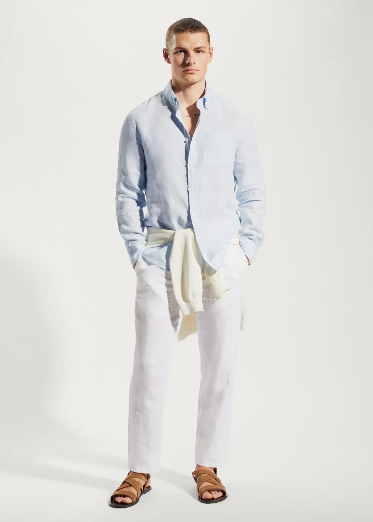 Mango 100% linen slim-fit shirt. a man in a light blue shirt and white pants. 