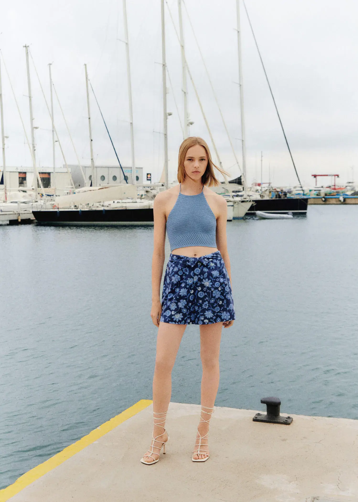 Mango Floral-print shorts. a woman standing on a dock near a body of water. 