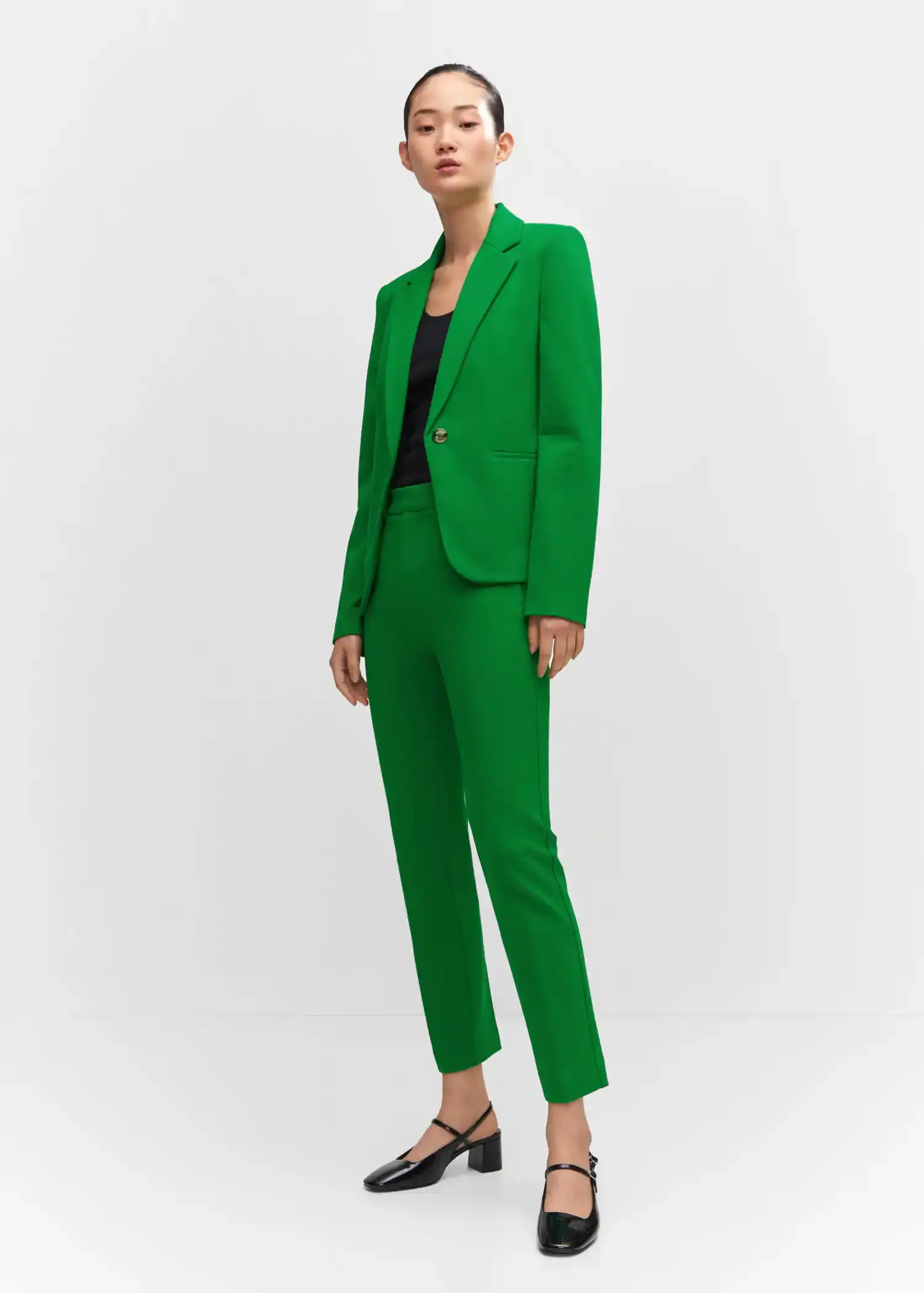 Mango Fitted jacket with blunt stitching. a woman wearing a green suit standing in a white room. 