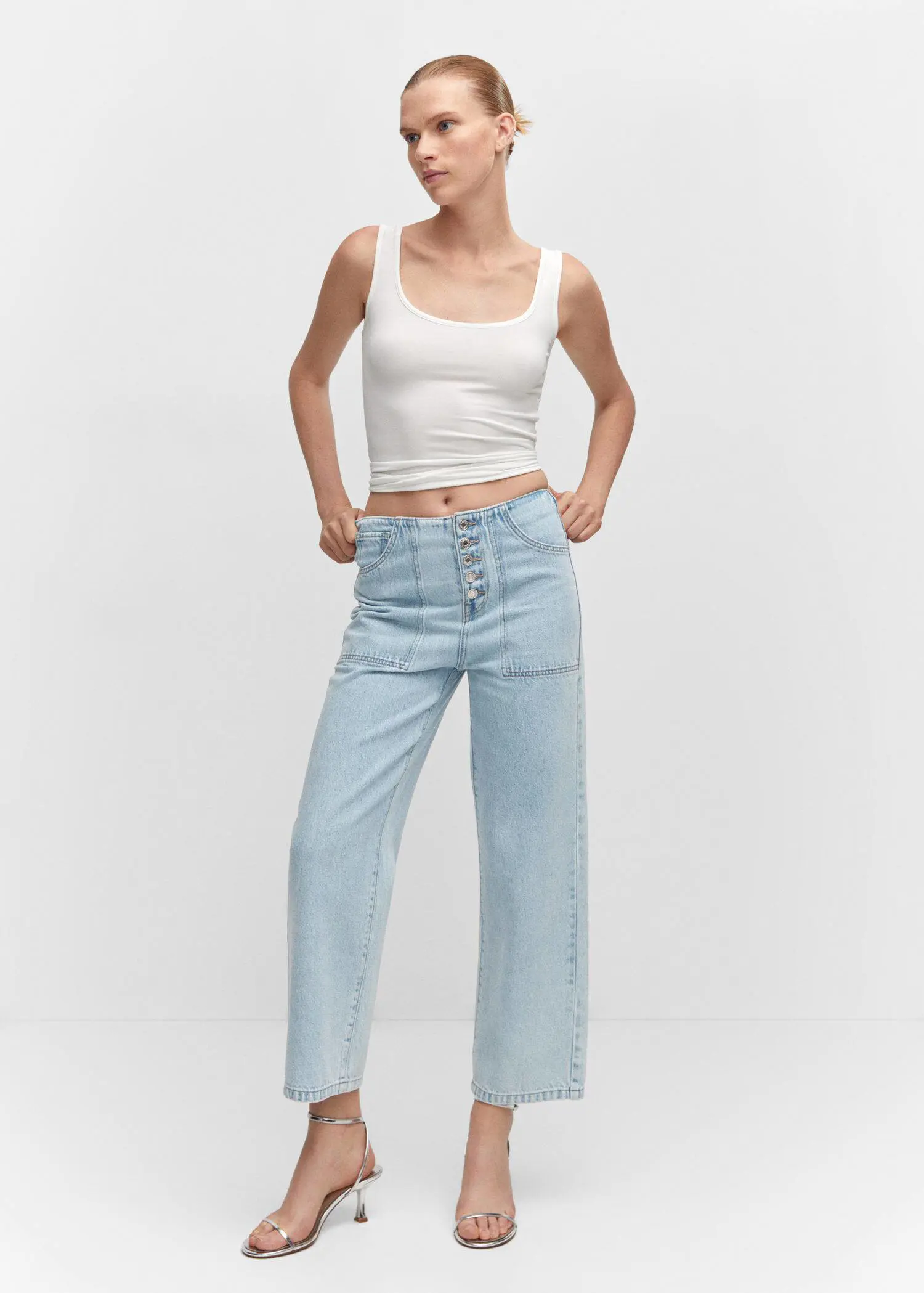Mango Cropped straight-leg jeans with buttons. a woman in a white tank top and light blue jeans. 