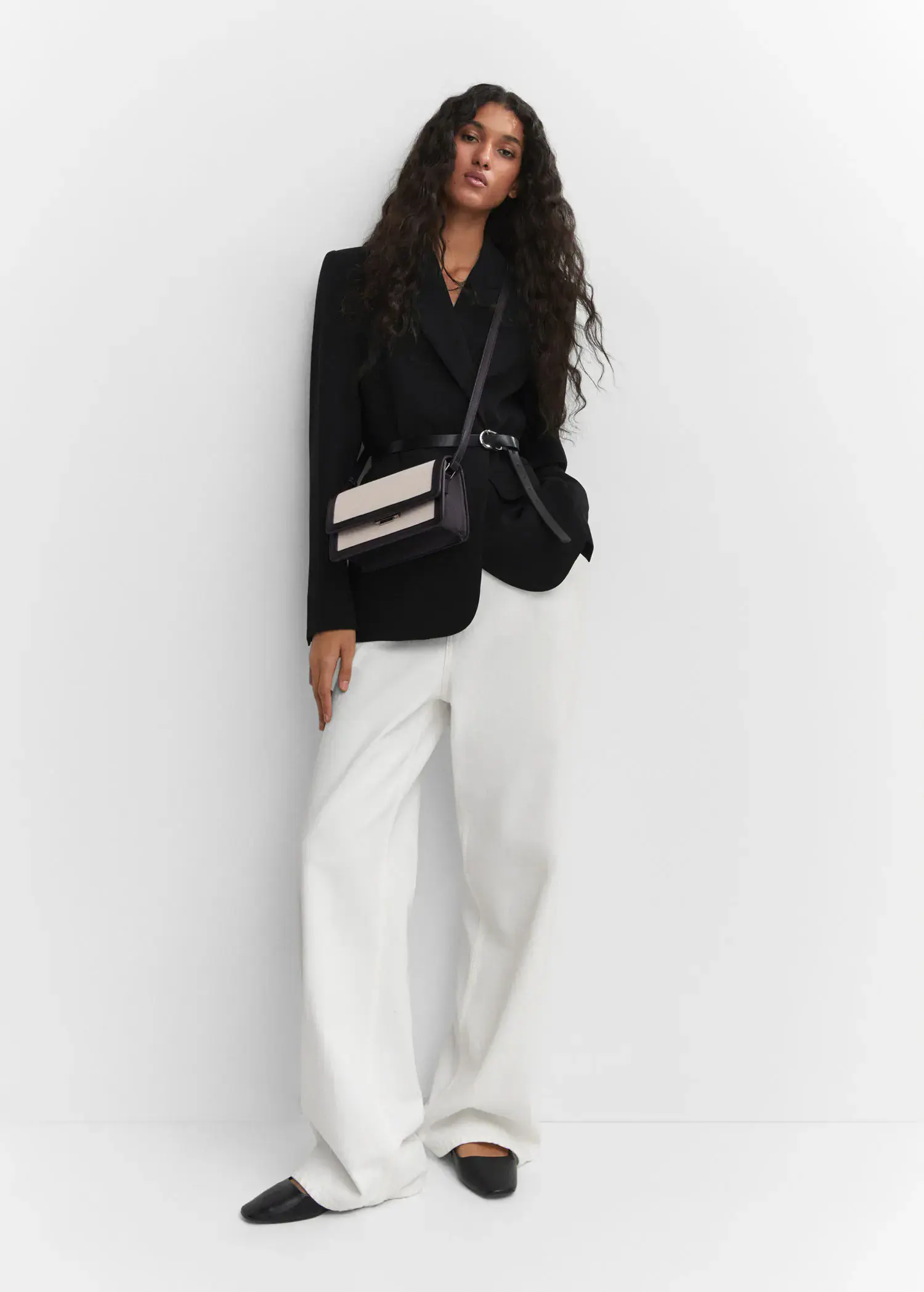 Mango Textured bag with flap. a woman wearing a black jacket and white pants. 