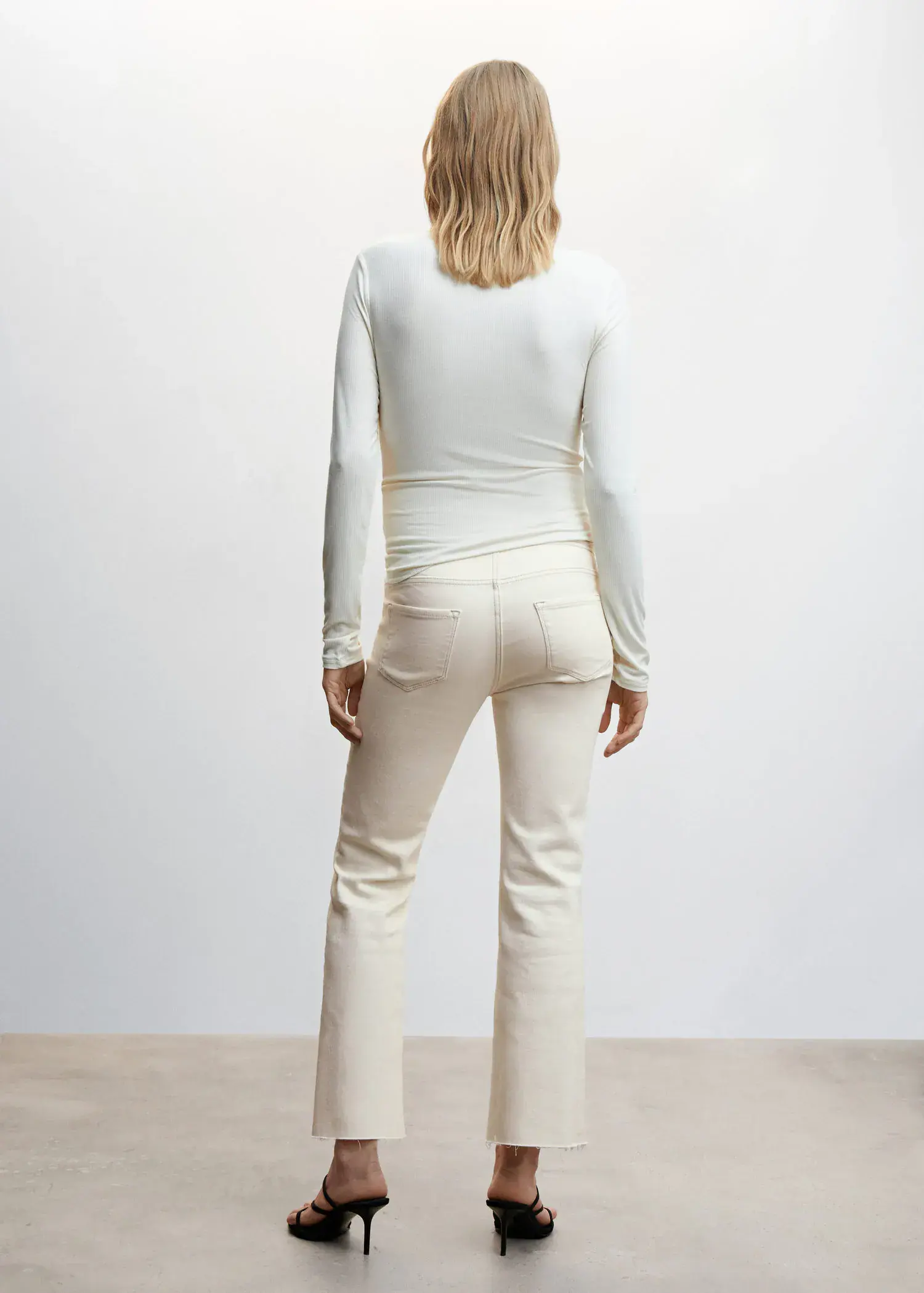 Mango Maternity flared cropped jeans. a woman wearing white pants and a white shirt. 