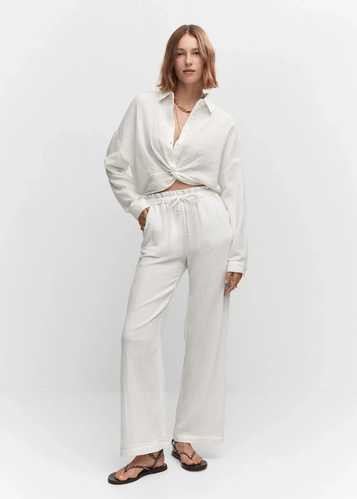 Mango Bow textured trousers. a woman in white shirt and pants standing in a room. 